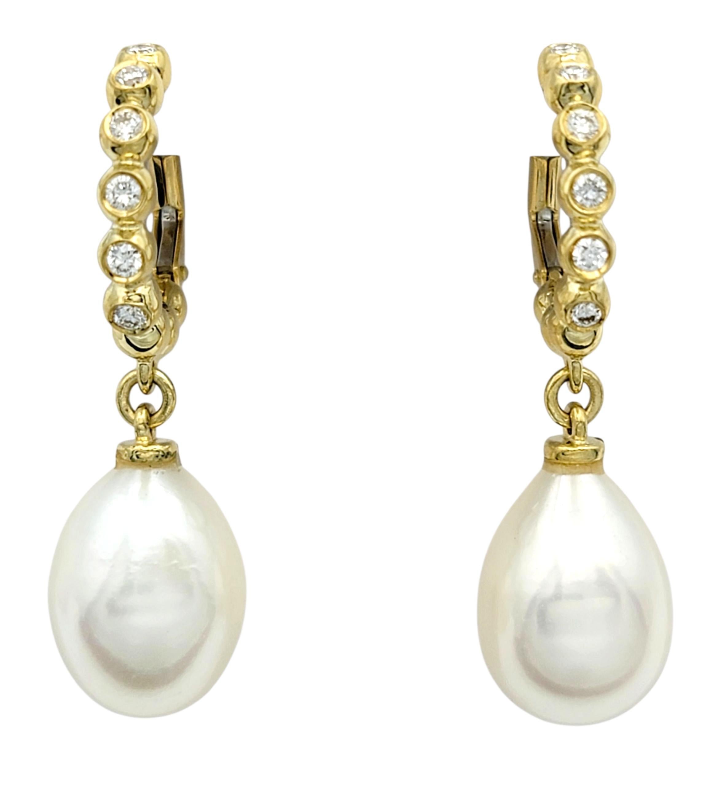 Ces boucles d'oreilles raffinées en or jaune 18 carats présentent des perles d'eau douce lumineuses suspendues sous une rangée étincelante de diamants sertis en chaton. Les perles présentent une surface lisse et lustrée qui contraste magnifiquement