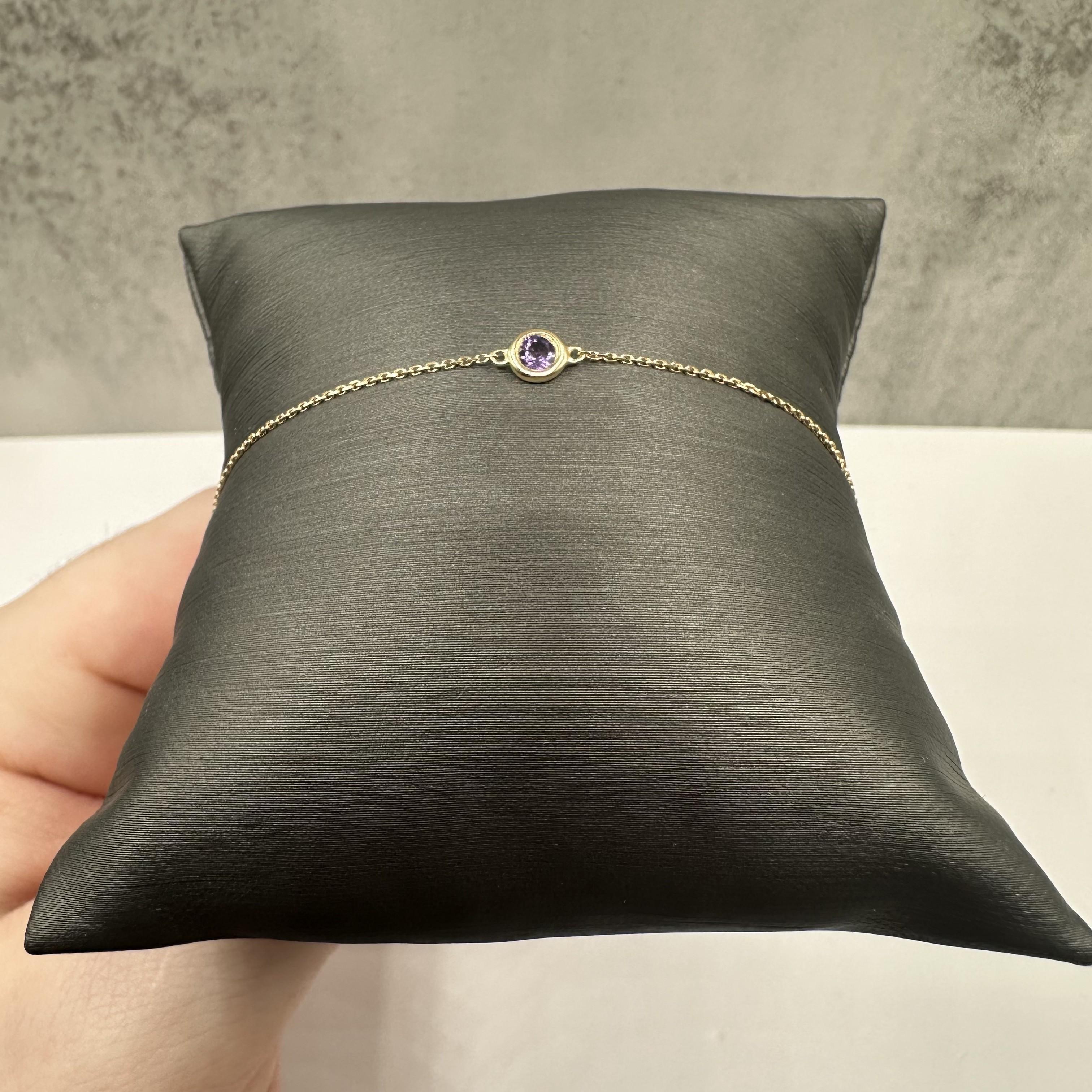 Esta elegante pulsera de piedras preciosas engarzadas en bisel, de oro amarillo de 14 quilates, tiene 0,12 quilates de piedras preciosas amatista redondas, de un intenso tono morado. La longitud es ajustable entre 15 y 20 cm, ofreciendo un ajuste