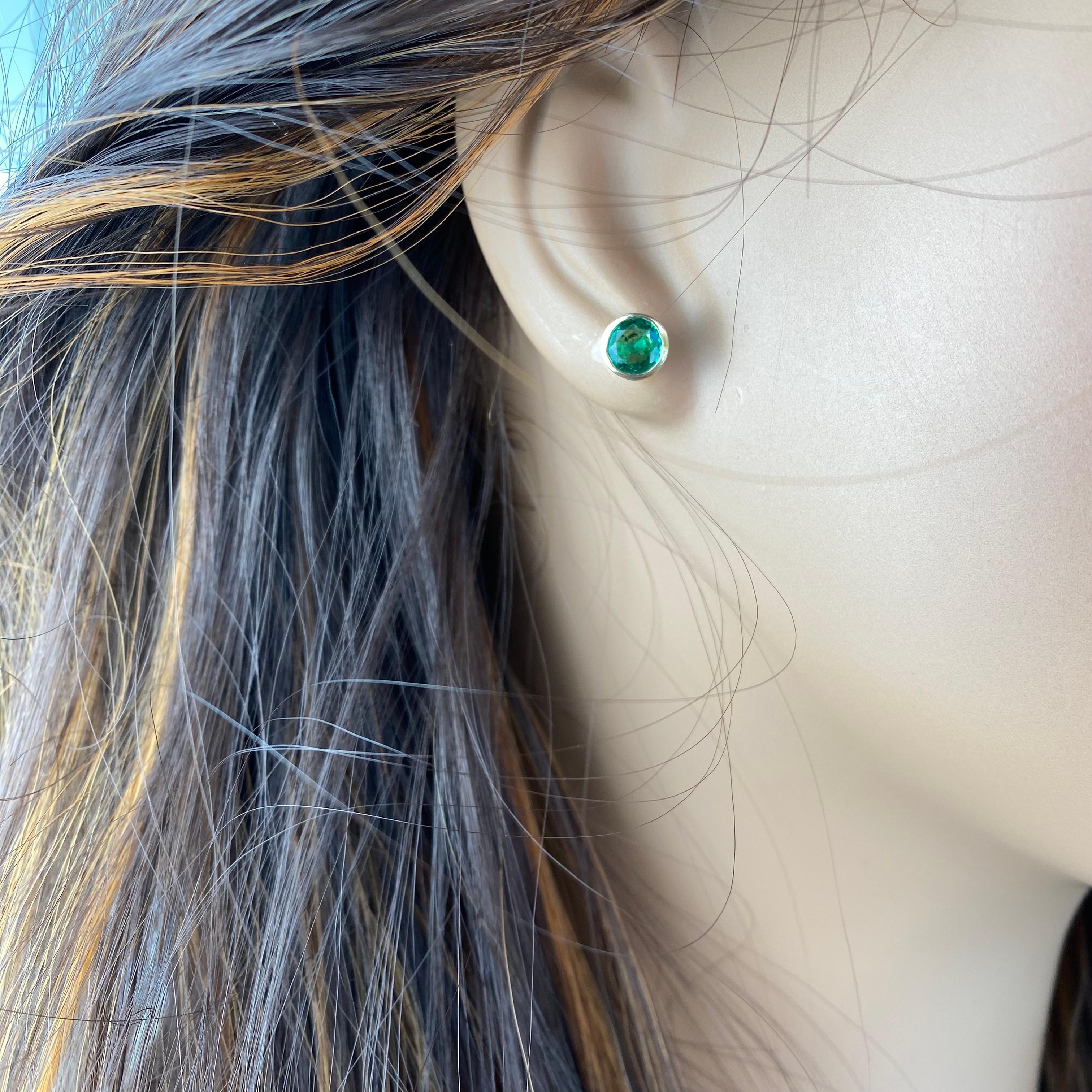 Indulge in the timeless elegance of these exquisite 14 Karat Yellow Gold Bezel Set Matched Pair Round Emerald Earrings. Each earring boasts a mesmerizing round Zambian emerald, meticulously bezel set to highlight its natural beauty and