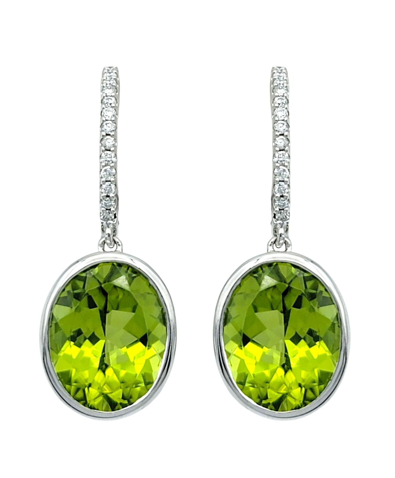These bright and beautiful earrings feature oval-cut green peridots suspended beneath diamond-accented hoop tops. The vibrant peridots are bezel-set, allowing the stones' vivid green color and natural brilliance to take center stage.

Each hoop is