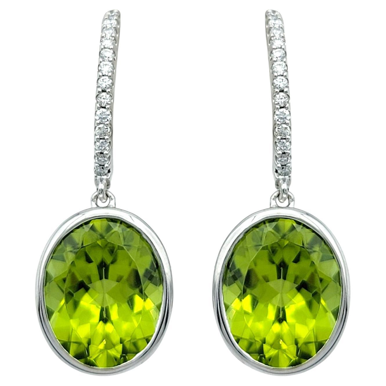Bezel Set Oval Cut Peridot Dangle Earrings with Diamonds in 14 Karat White Gold