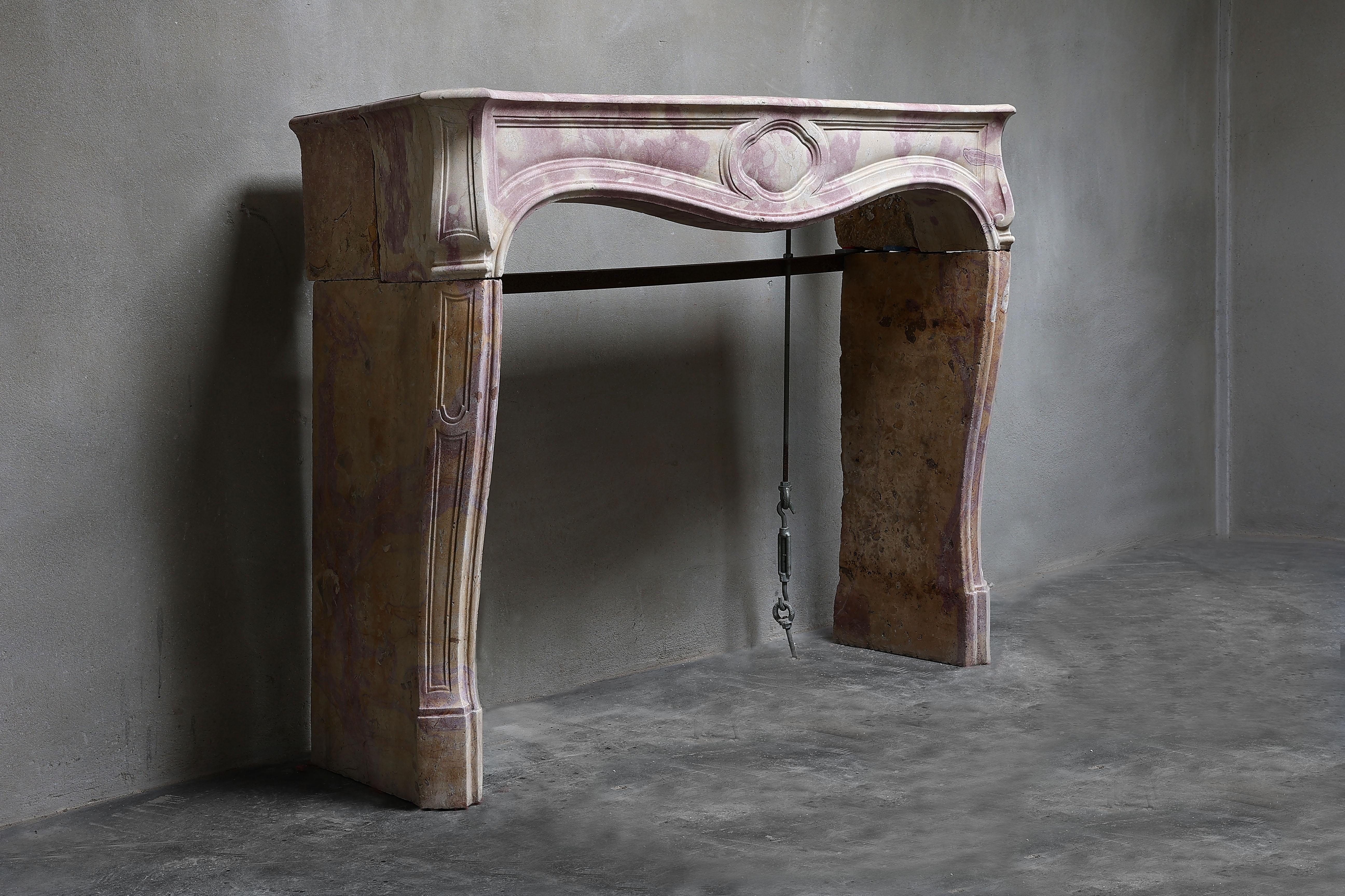 Very special antique fireplace of bi-color marble stone. This marble stone gives a unique color to the fireplace. It is a unique fireplace in our collection and is in the style of Louis XV with beautiful curves and ornaments. A chimney from the 19th