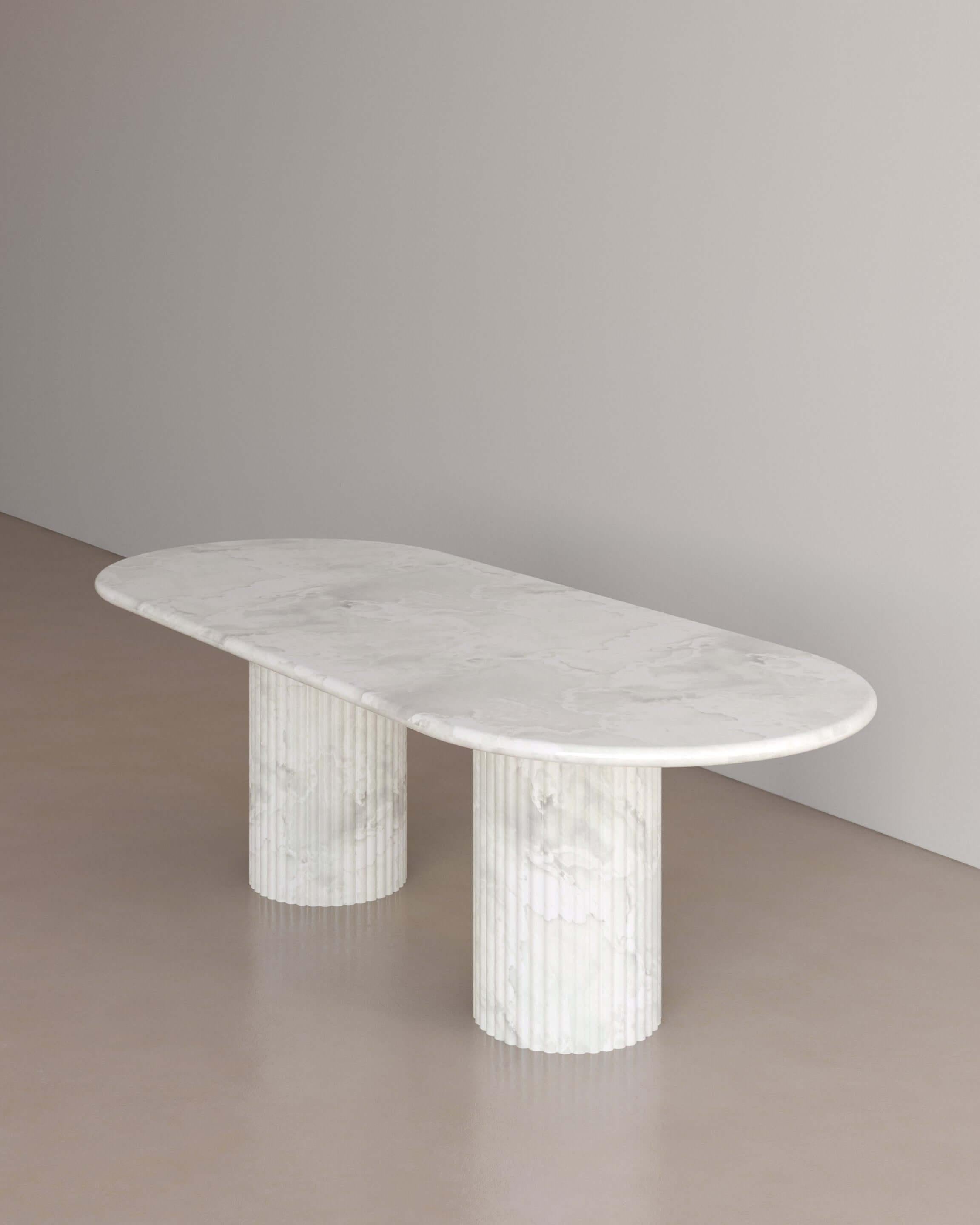 The Essentialist brings you The Antica Dining Table II in Bianco Onyx. An oval table top resolved by smooth bullnose edges rests on two supporting pillars. Architectural form is refined by artistic expression echoing Roman culture. This table,