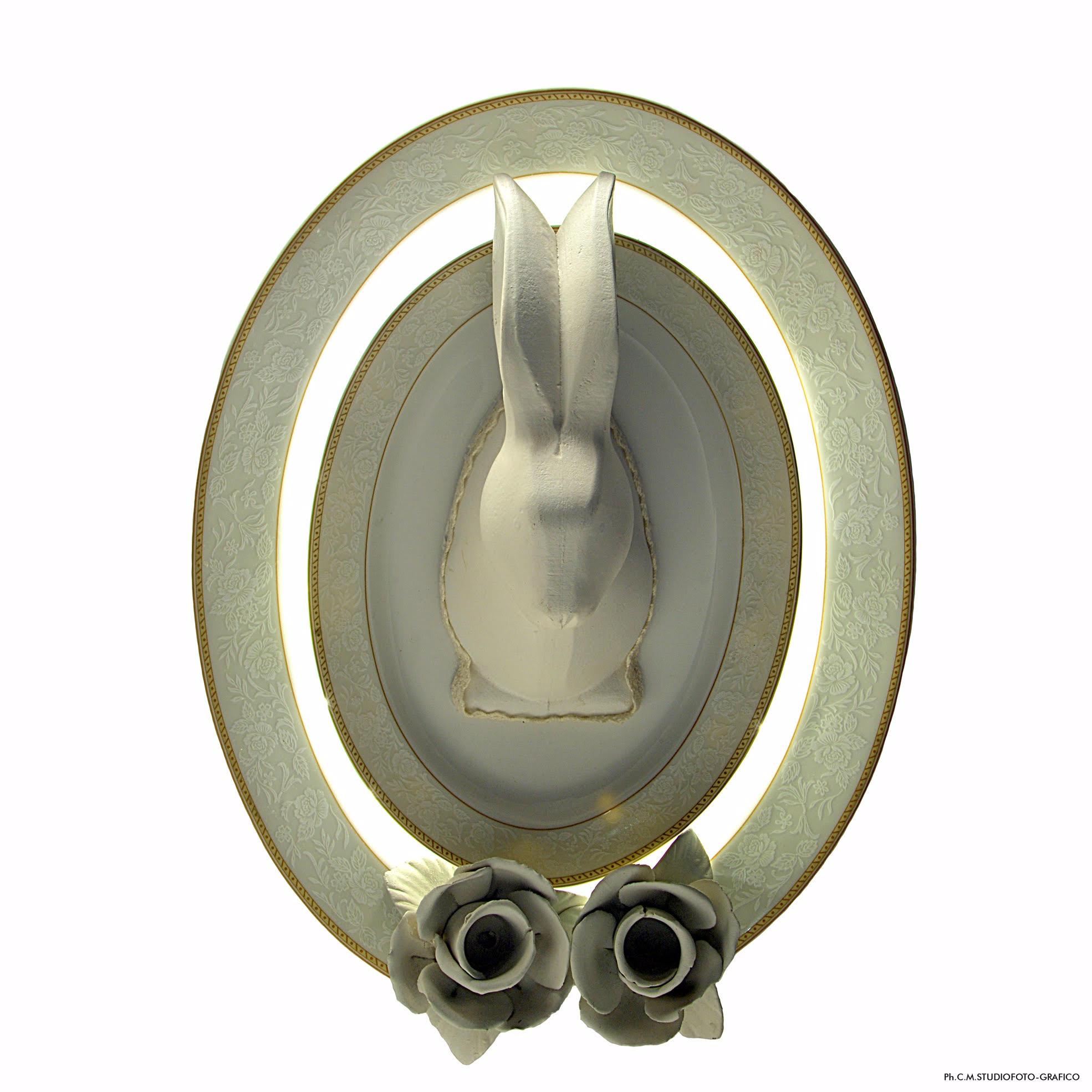 Wall lamp consisting of a pair of oval white porcelain plates with decorations, white wooden rabbit and ceramic roses.
LED band around the smaller plate.
Hanging system via metal ring and cloth.
Light and emotion are inseparable, a poetic language