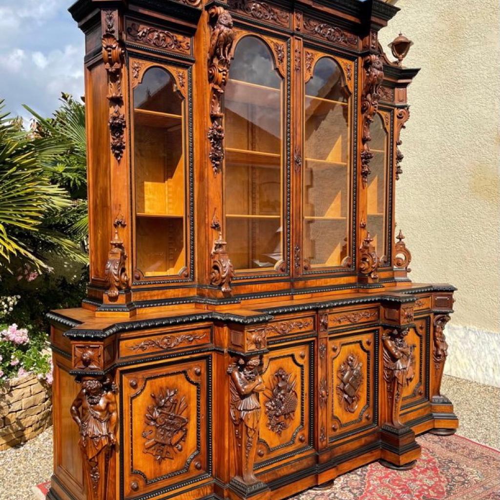 Sumptuous and monumental castle library in walnut and ebony. It is entirely sculpted and represents the Goddess Athenaeum and the God Dyonisos. Athenaeum or Athena is the goddess of war, wisdom, strategy and inventions but also protector of heroes,