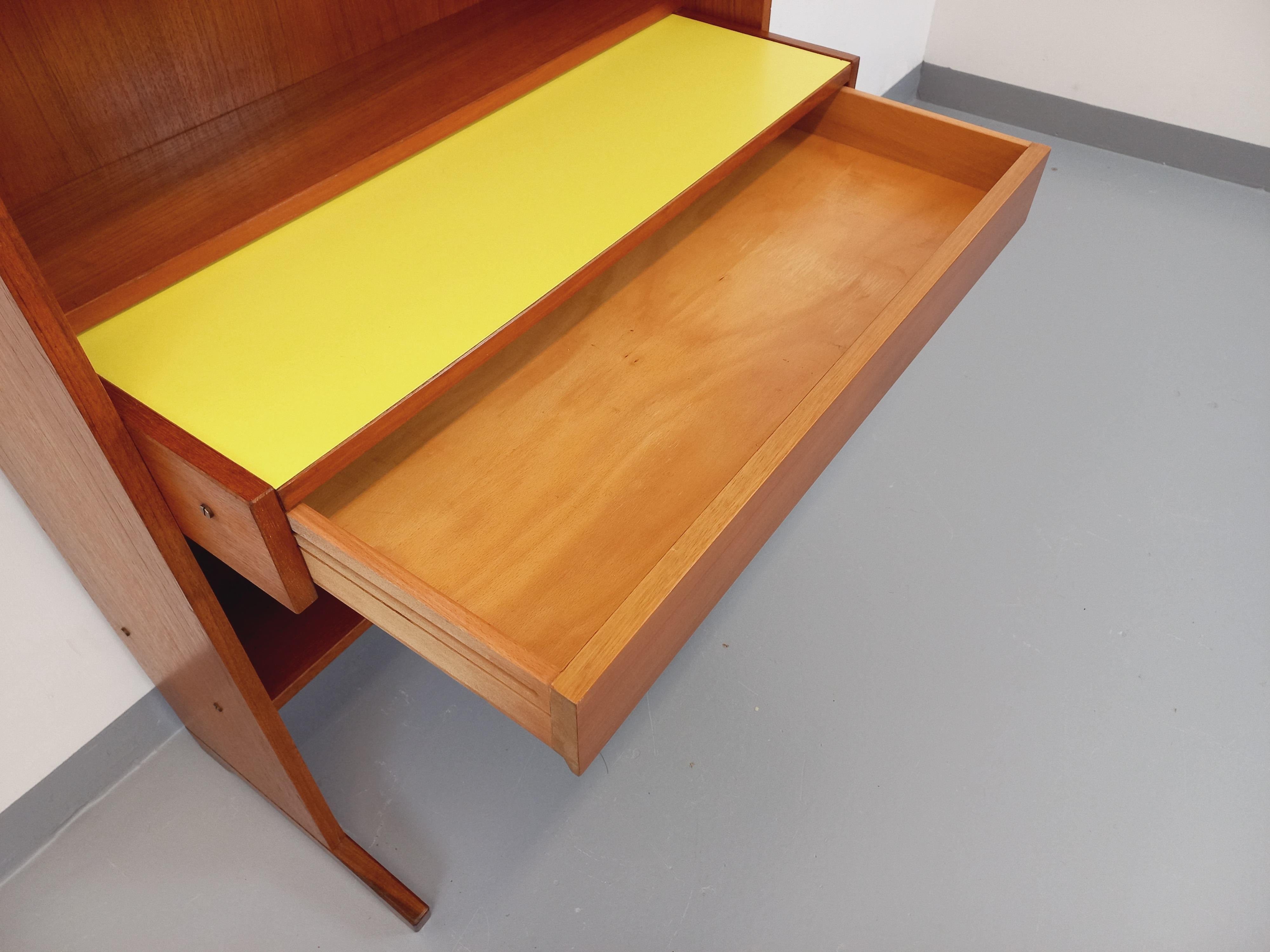 Bibliothèque étagère vintage style scandinave des années 60, très beau design italien, tout en teck, 4 étagères ouvertes, 1 partie secrétaire/bureau coulissant avec plateau en mélaminé jaune, 1 grand tiroir, 2 portes coulissantes avec de jolis