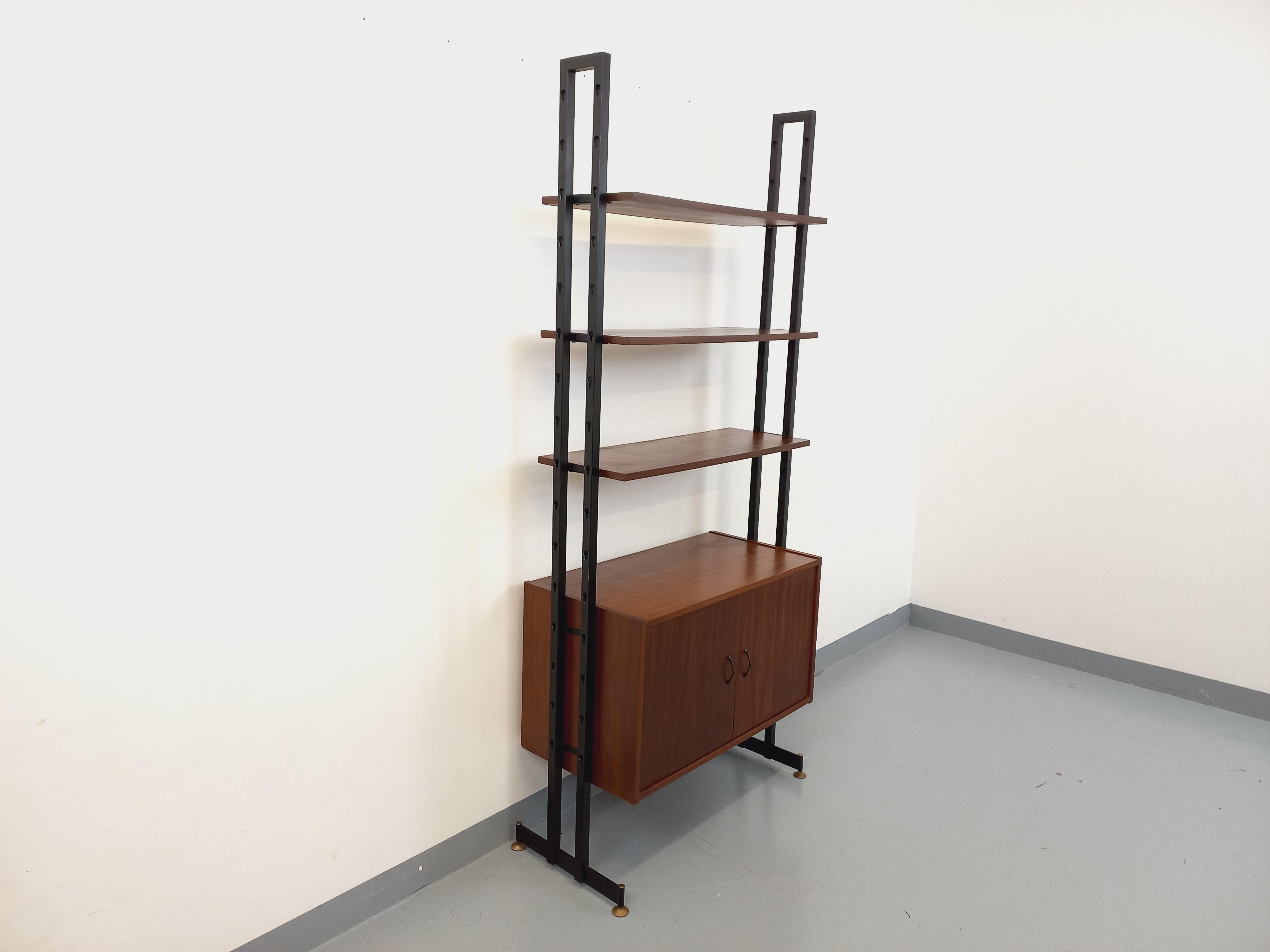 Bibliothèque étagère vintage style scandinave des années 60, design italien, en teck et métal noir, pieds en laiton réglables pour ajustement au sol, 3 étagères ouvertes, 1 module / caisson fermé par 2 portes avec poignées noires et étagère