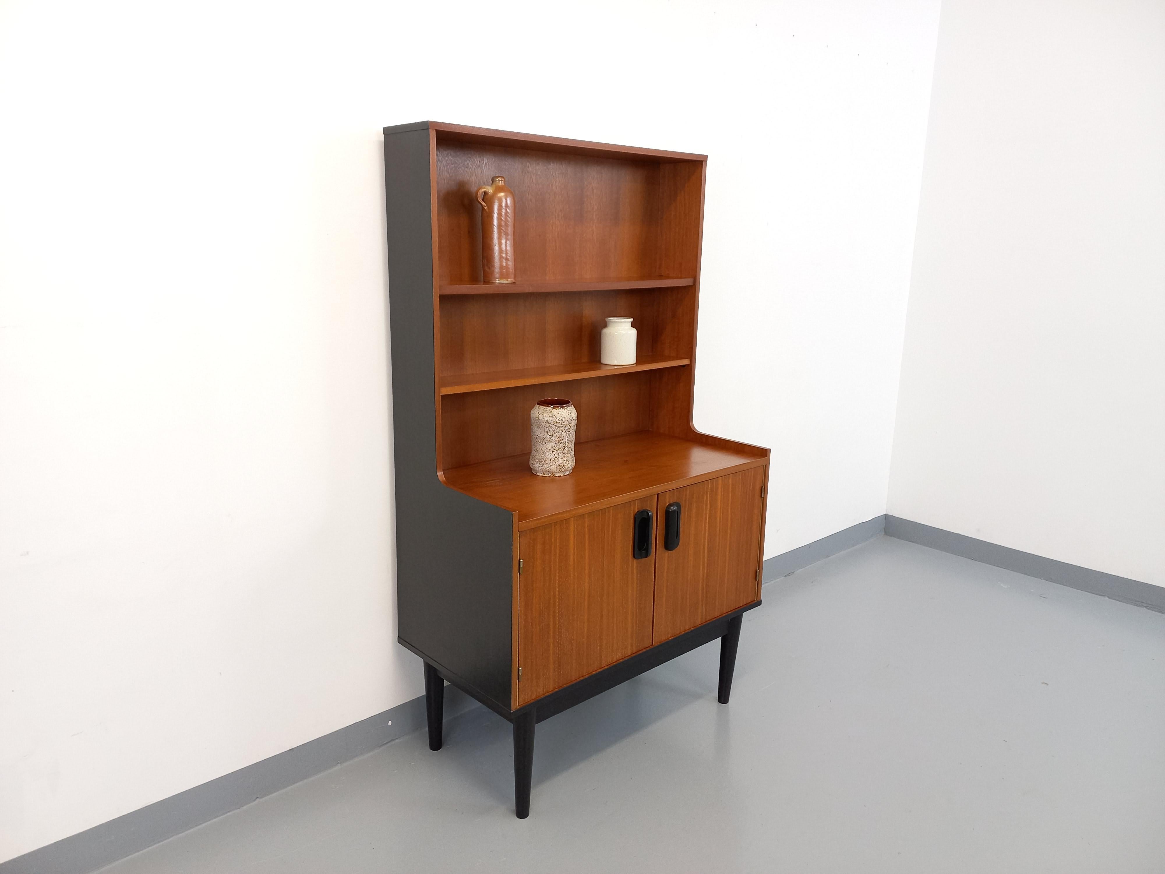 Bibliothèque étagère vintage des années 60, style scandinave, en teck, pieds compas, côtés, poignées et piétement peints en noir, 2 étagères ouvertes et 2 portes avec étagère intérieure, très bon état général avec quelques signes du temps qui