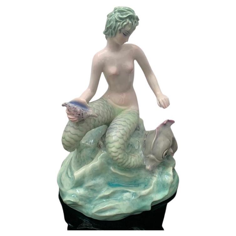 Bicauda Meerjungfrau mit Muschel auf dem Felsen und mythologischem Fisch