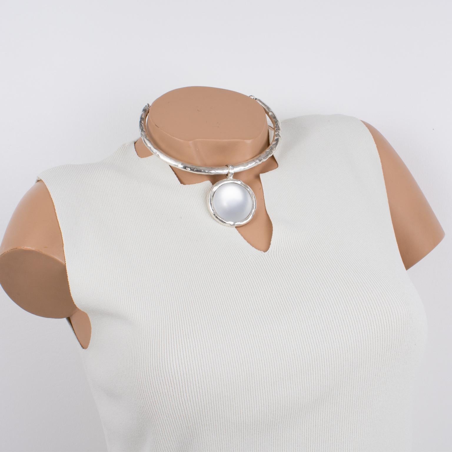 This fabulous modernist silvered metal choker necklace by Nelly Biche de Bere, Paris, features a rigid around-the-neck band with a hand-made feel design complimented with a round pendant. The pendant is ornate with a massive arctic white resin