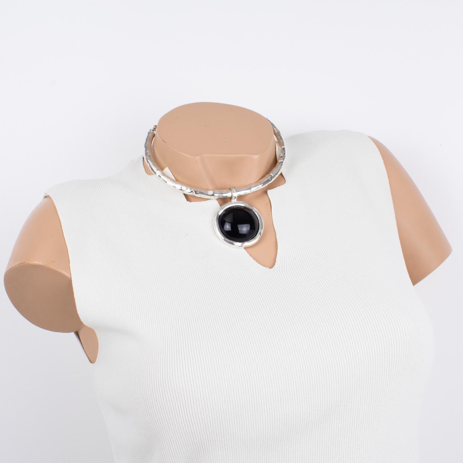 This elegant modernist silvered metal choker necklace by Nelly Biche de Bere, Paris, features a rigid around-the-neck band with a hand-made feel design complimented with a round pendant. The pendant is ornate with a massive black resin cabochon. The