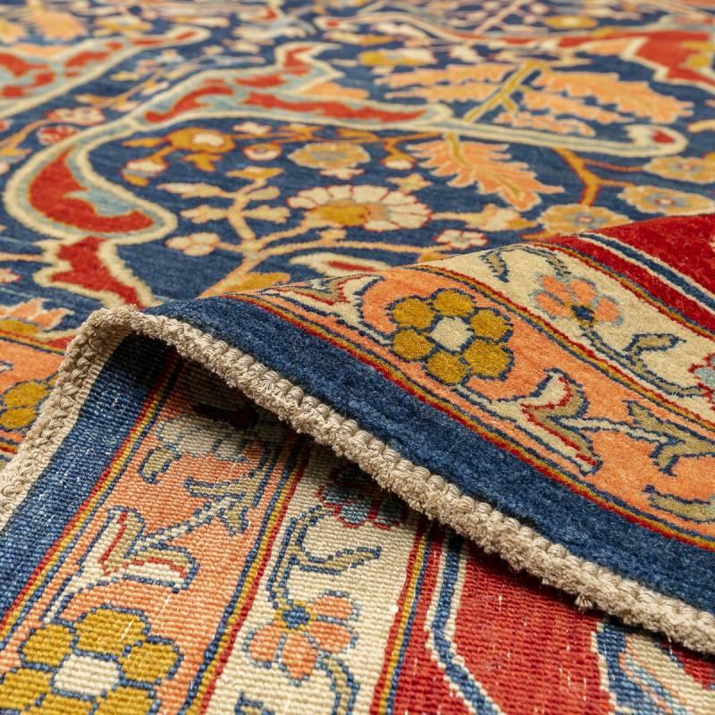Persian Bidjar design rug of palmette flowers in reds and blues on a blue and red background in the central field.
- The rest of the decorative elements follow linked patterns of floral figures and palmette along its border on a red background.
-