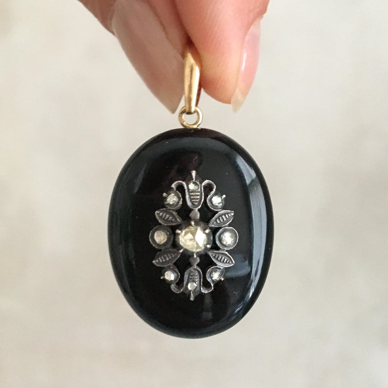 A beautiful Late Victorian diamond and onyx mourning locket pendant. On top, the locket pendant is decorated with a silver flower and leaves which are adorned with rose cut diamonds. The locket pendant dates from the late Victorian period, circa