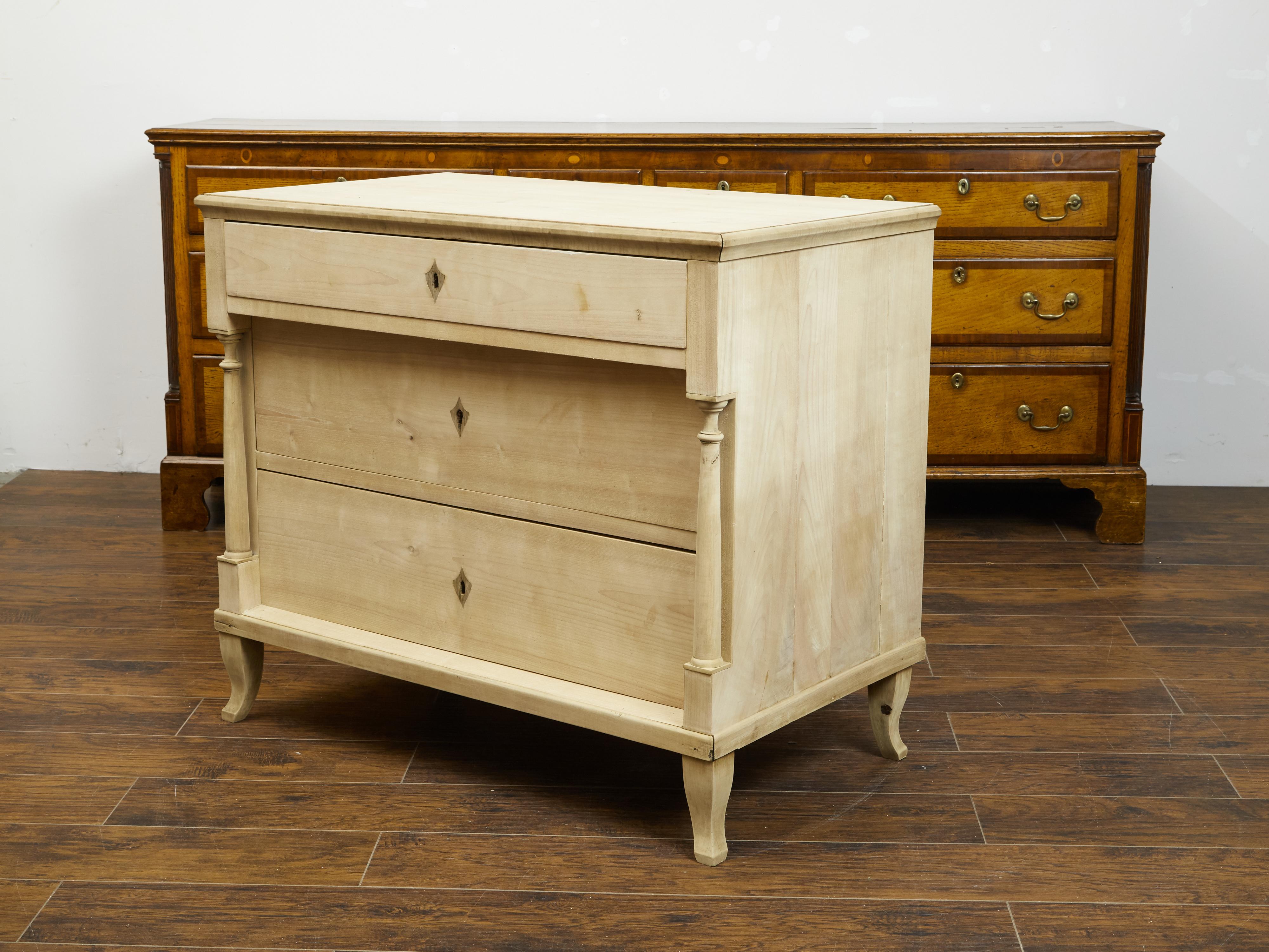 An Austrian Biedermeier bleached wooden commode from the 19th century, with three drawers and petite columns. Created in Austria during the Biedermeier period, this freshly bleached commode features a rectangular top sitting above three drawers, the