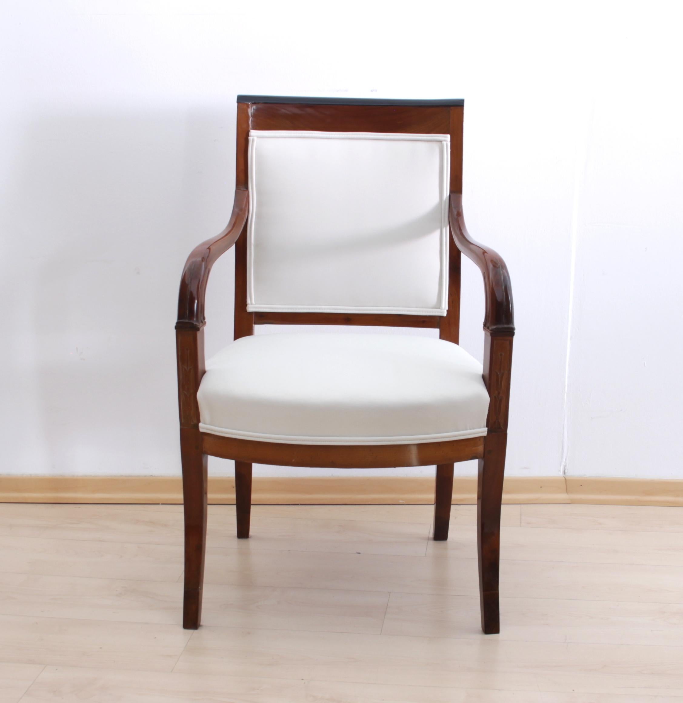 Elegant french Restauration Armchair from about 1820.

Cherry solid wood with carvings at the frontside of the armrests depicting vases and flower ranks. Ebonized strip at the top of the backrest. Great seating comfort.
The upholstery fabric is a
