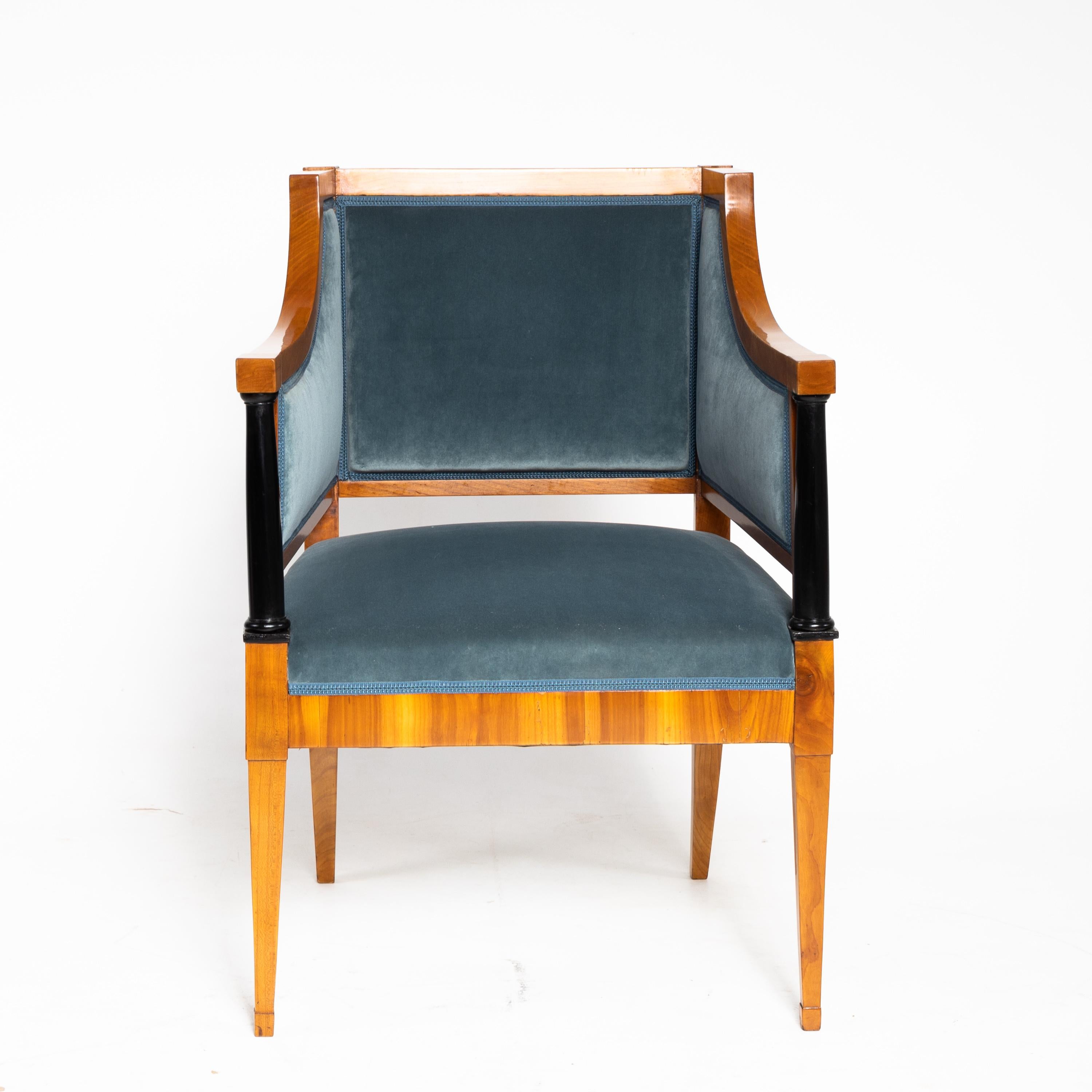 Biedermeier armchair on square pointed feet at the front and slightly flared sabre legs at the back. The armrests start at the same height as the straight backrest and then lower themselves onto ebonized full columns. The armchair is veneered in