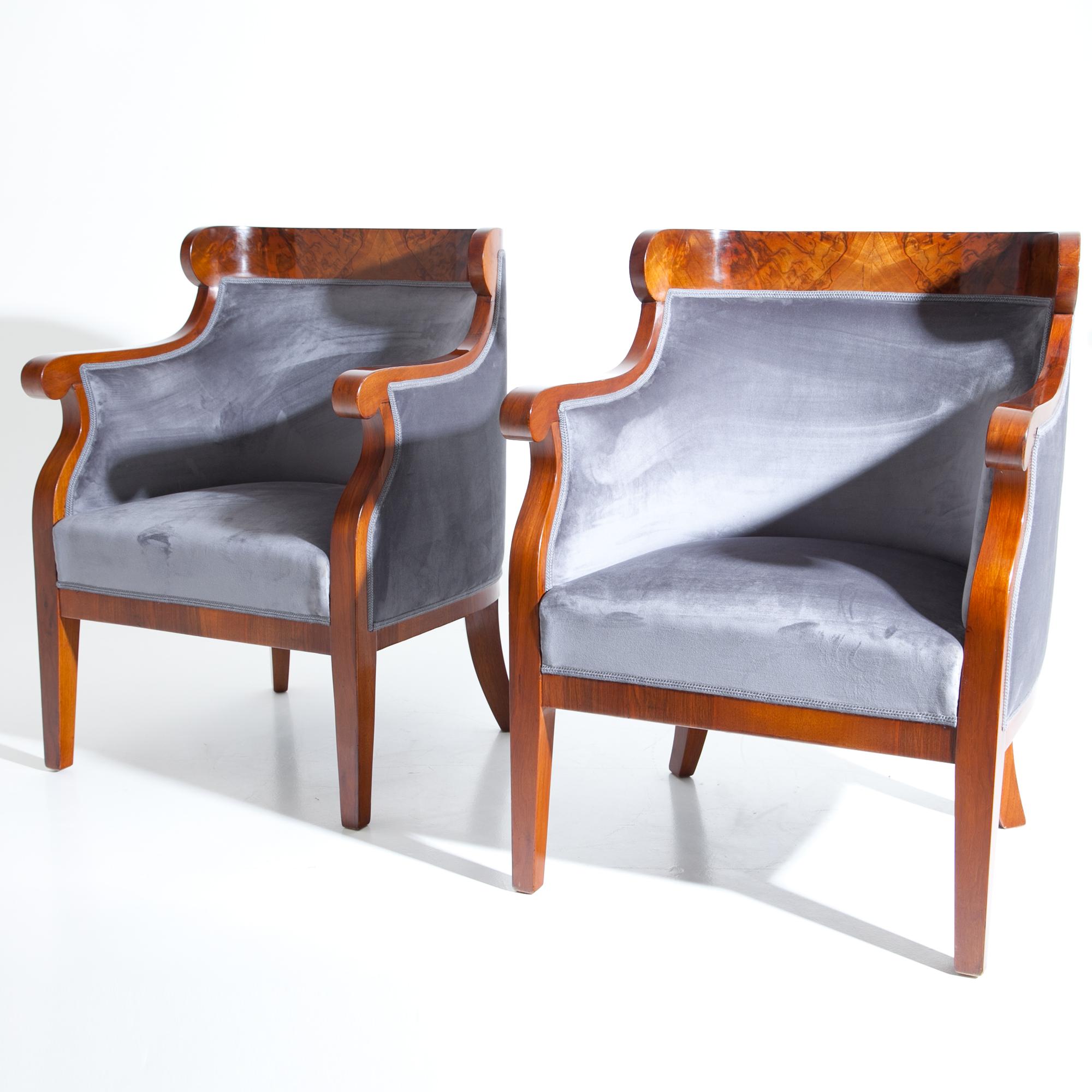 Pair of Late Biedermeier armchairs, veneered in walnut. The elegantly curved backrest turns into the armrests and is upholstered from both sides. These bergere chairs were refurbished and reupholstered with a high quality grey suede.