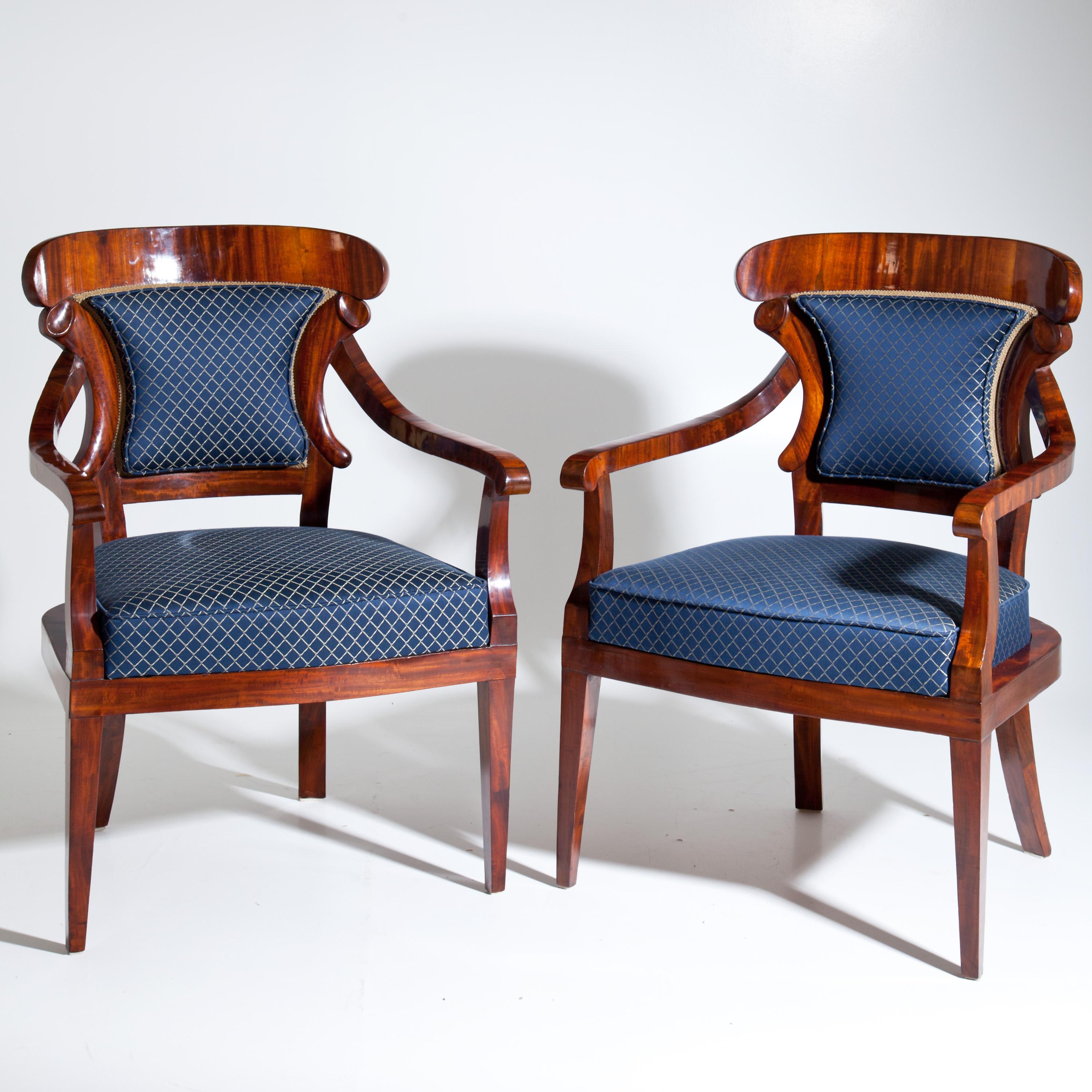 Pair of Biedermeier mahogany armchairs with curved armrests and shovel-shaped backrests. The vertical struts of the backrests are modelled on stylised cornucopias. The seats and backrests are newly covered with a blue satin fabric with a gold