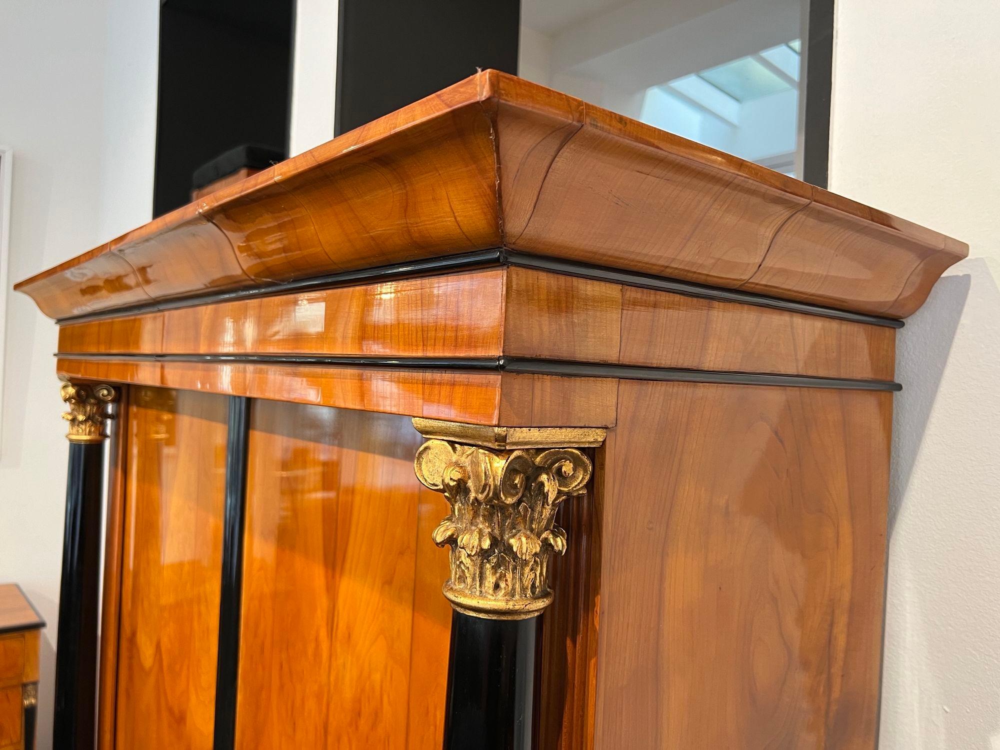 Beautiful original Biedermeier armoire or wardrobe from Austria around 1820.

Cherry wood veneered.
Ebonized full columns with corinthian capitals in old gilding.
Original brass fittings and iron lock.
Inside with four shelves covered in black