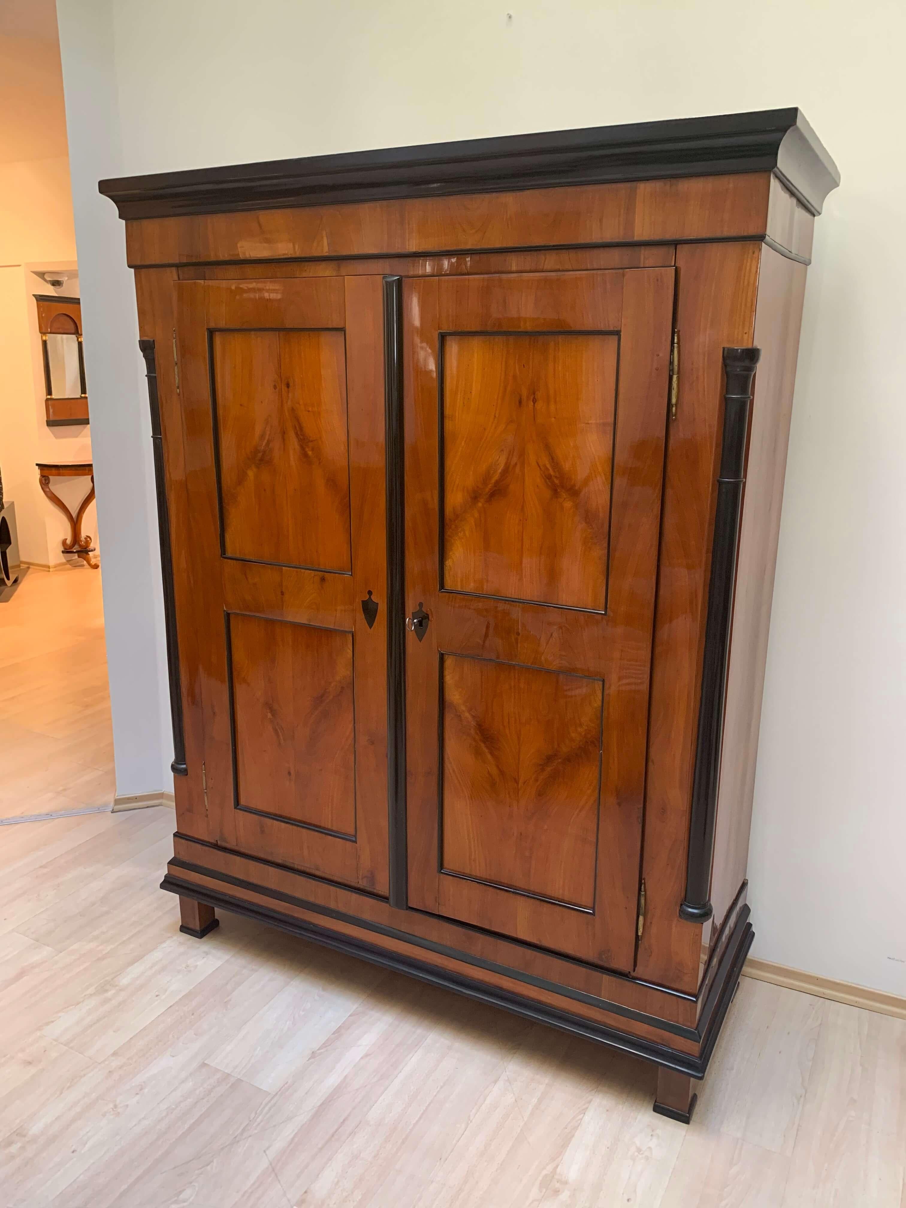 Wonderful two-doored Biedermeier armoire from Franconia, South Germany, circa 1830

The framework is made of cherry solid wood. At the frontside, it has four cherry veneer fillings with an amazing and book-matched grain. 
The half-columns at the