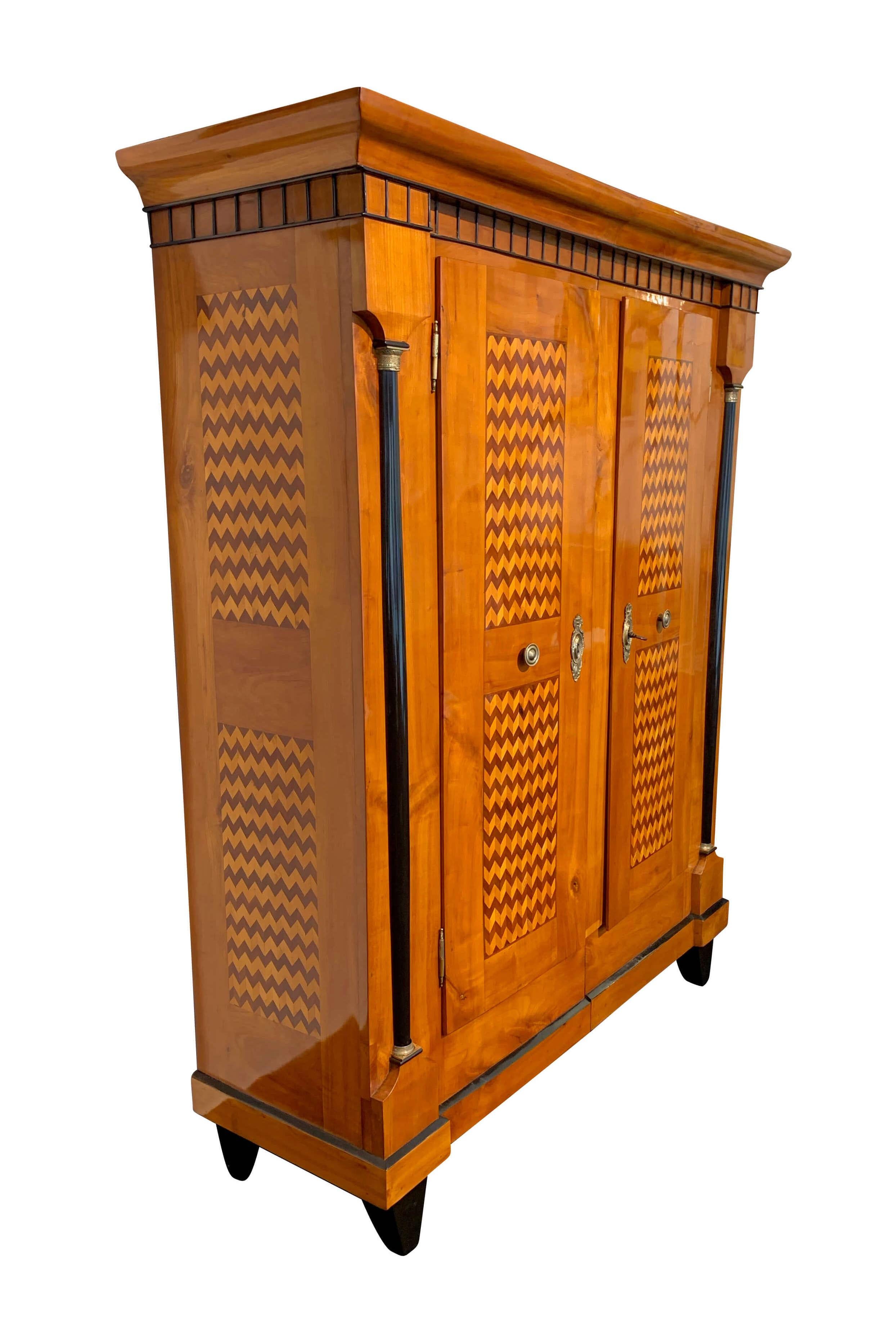 Wonderful original Biedermeier armoire or wardrobe from Lake Constance Area, South Germany, circa 1820.

Amazing bright and friendly cherry veneer and elaborate plum and maple inlay band at the front and sides. 
Ebonized half-columns with