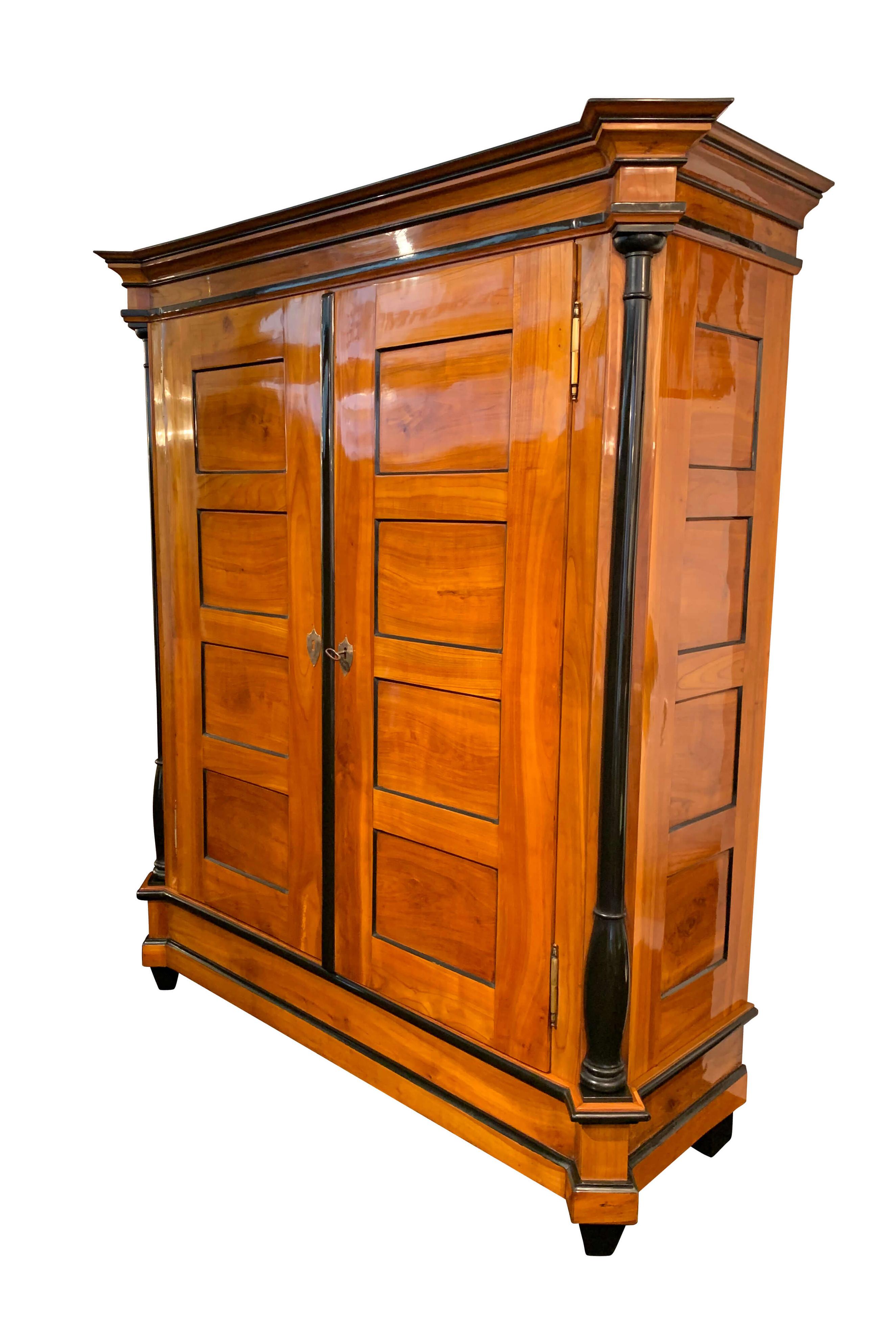 Stately, large Biedermeier armoire or wardrobe in cherry solid wood from Southwest Germany, circa 1820.

Solid cherry tree, hand-polished with shellac (French polish). Some ebonized parts, including three-quarter columns at the corners.
Beautiful