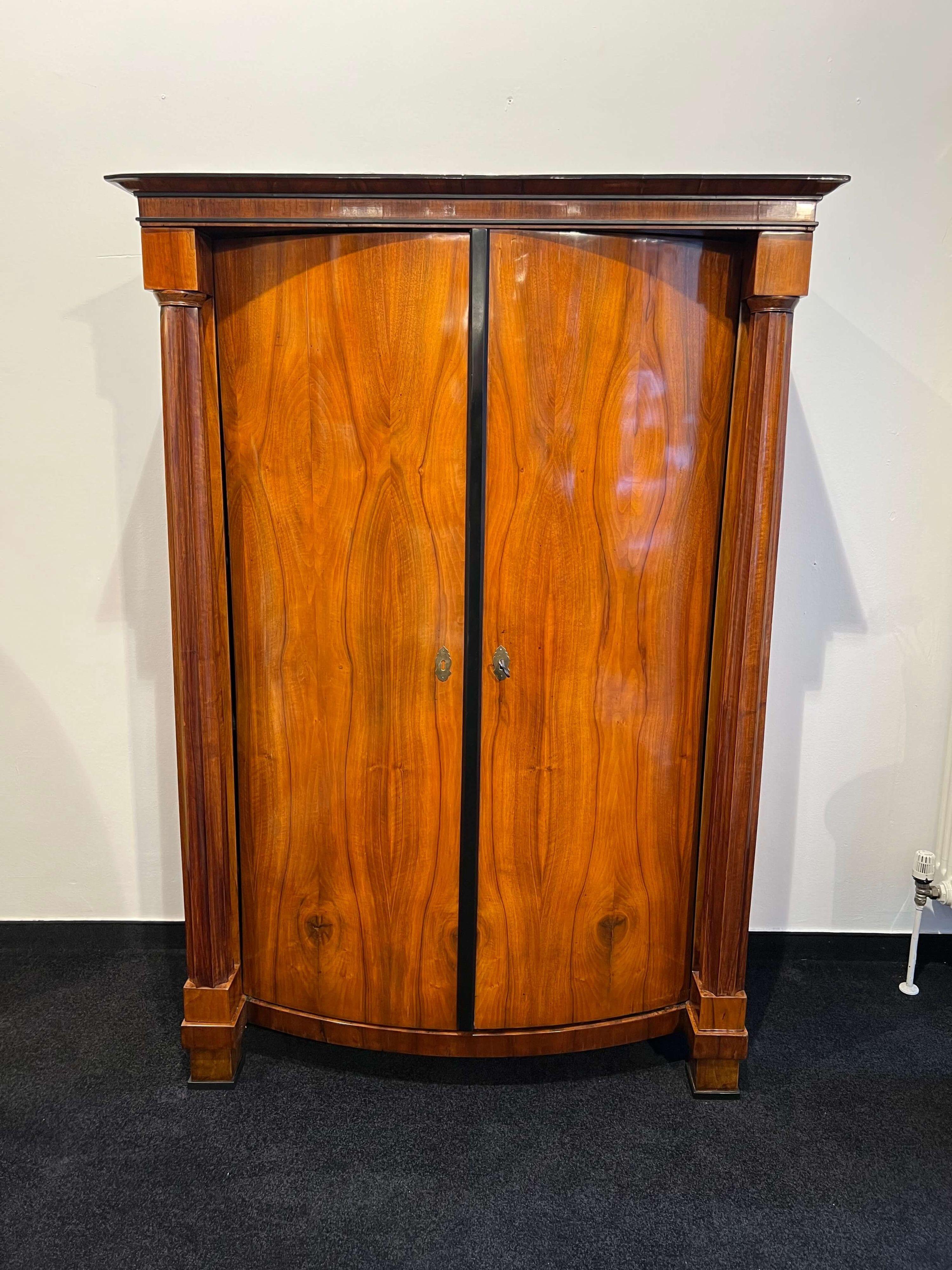 Bellissimo armadio/guardaroba/armadio Biedermeier originale restaurato in noce impiallacciato con fronte convesso e colonna piena scanalata di Vienna, Austria, 1825 circa.
Impiallacciato in noce su legno di conifera con una meravigliosa venatura
