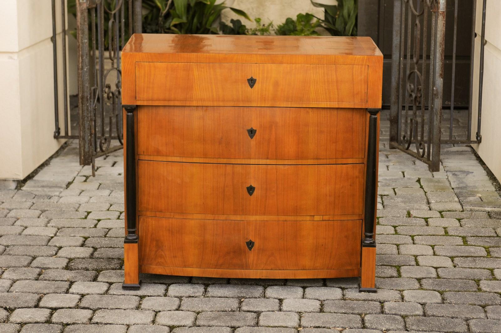 An Austrian Biedermeier walnut veneered four-drawer commode from the late 19th century, with ebonized wood columns and convex façade. Born in Austria during the third quarter of the 19th century, this stylish commode features a rectangular top