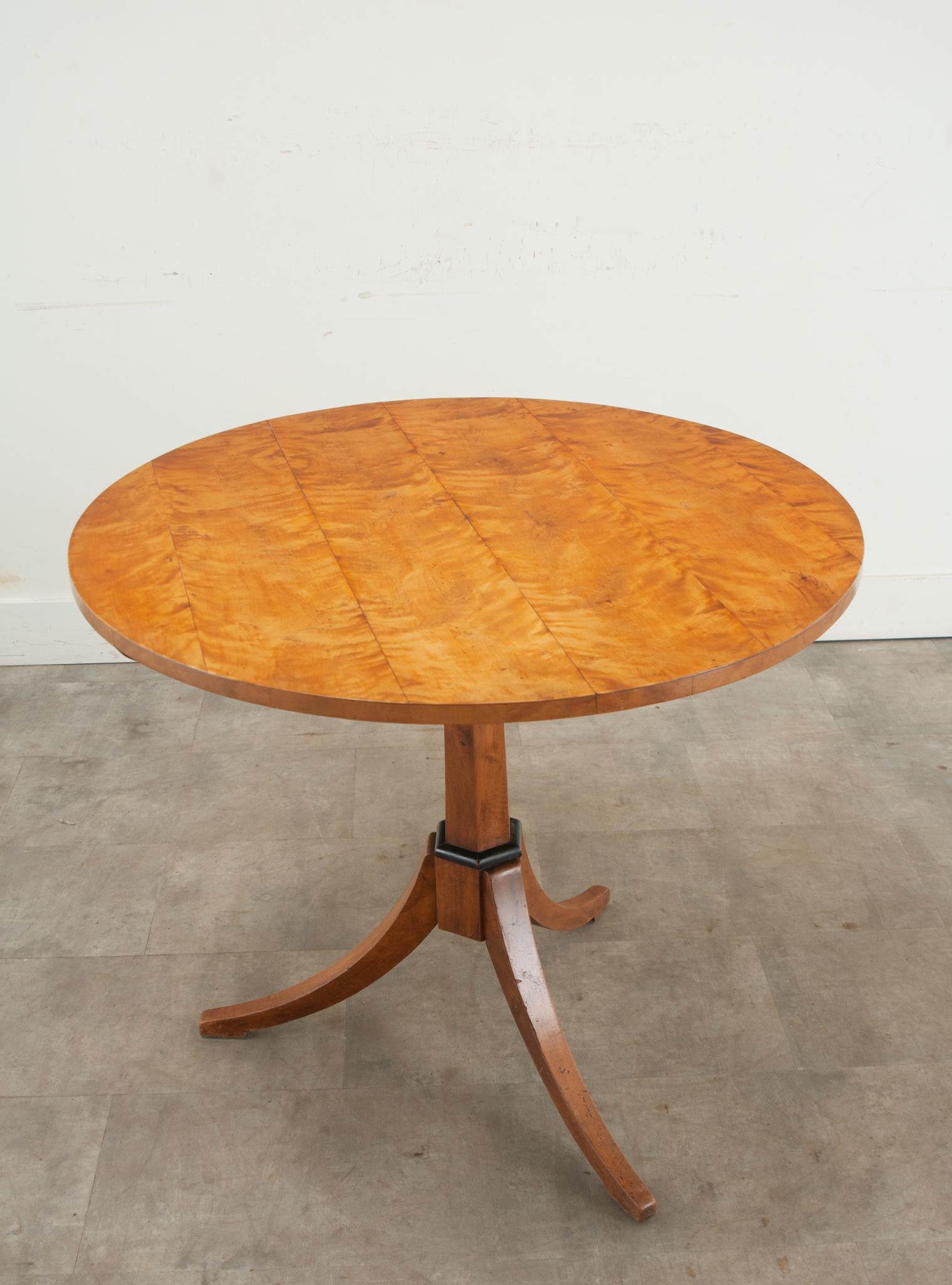 A Swedish tilt-top round table made in the 1800’s. The top is made from wonderfully colored birch with handsome grain patterns and rests over a geometric pedestal base with three splayed legs. There’s a touch of ebonized trim giving this table depth
