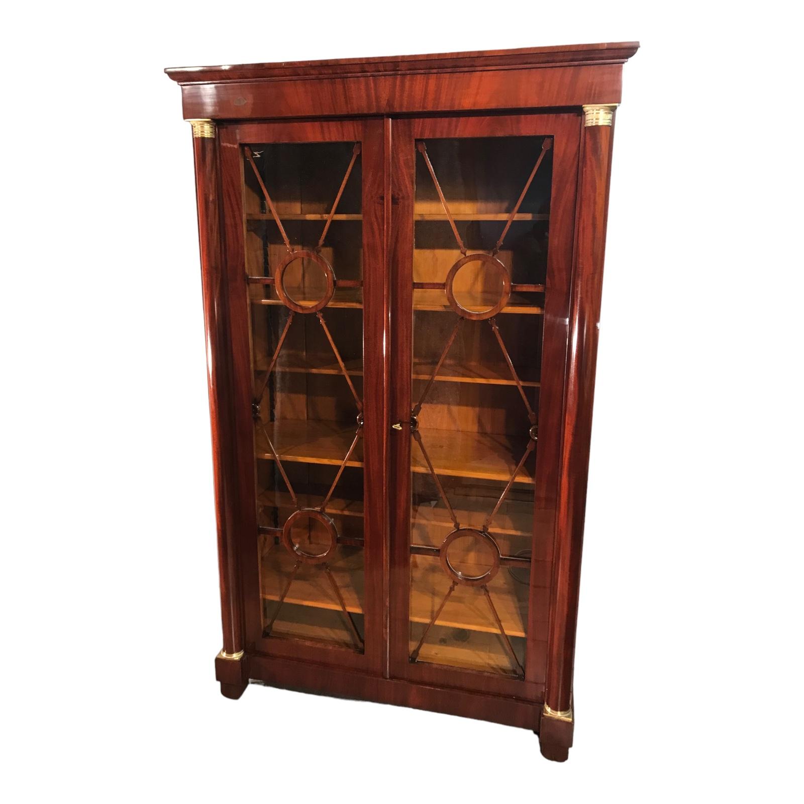 This unique antique Biedermeier library cabinet dates back to the early Biedermeier period 1810-20 and comes from Germany. It features a walnut and mahogany veneer on softwood. The two doors are framed by columns with their original brass capitals