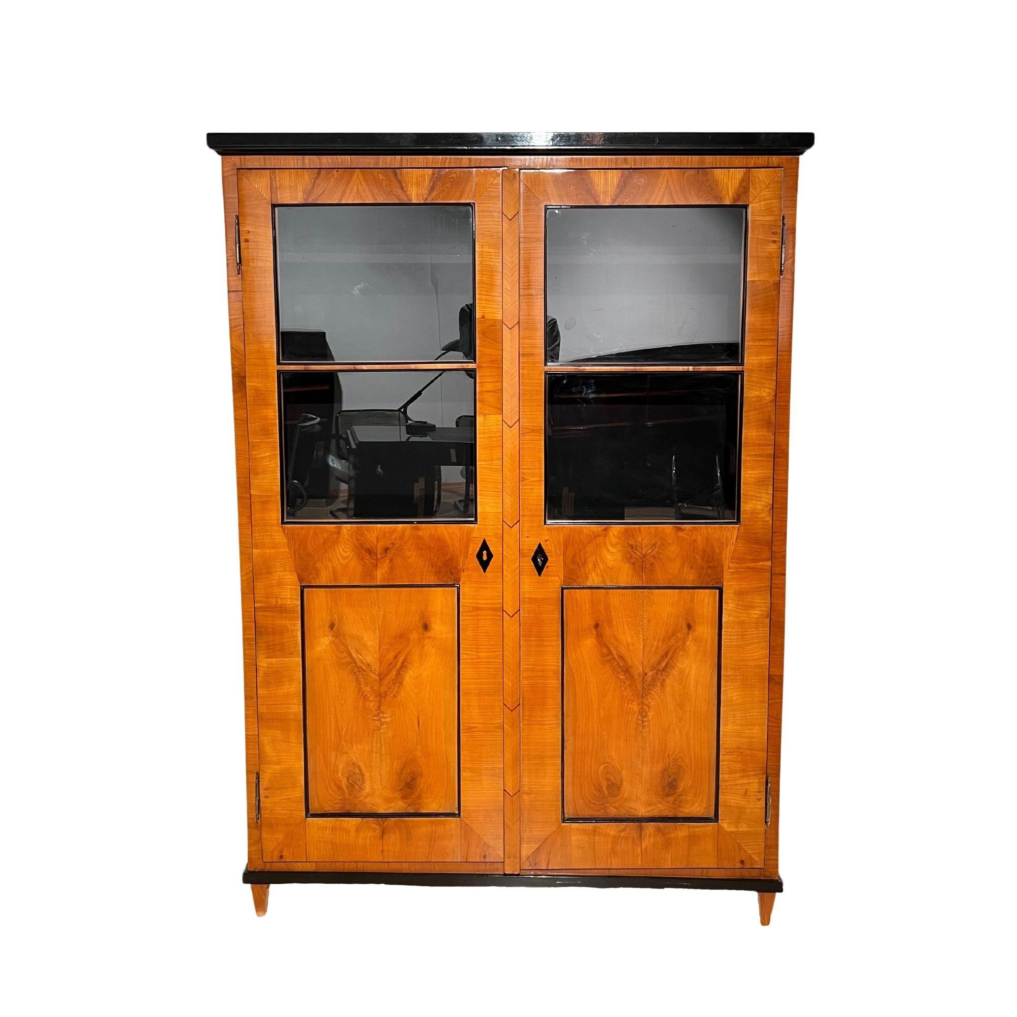 Beautiful, straightlined Biedermeier bookcase or display cabinet in cherry wood veneer from southern Germany around 1820.
* Blonde book-matched cherry wood veneered on softwood.
* The door's end strip is also a mirror image and veneered on three
