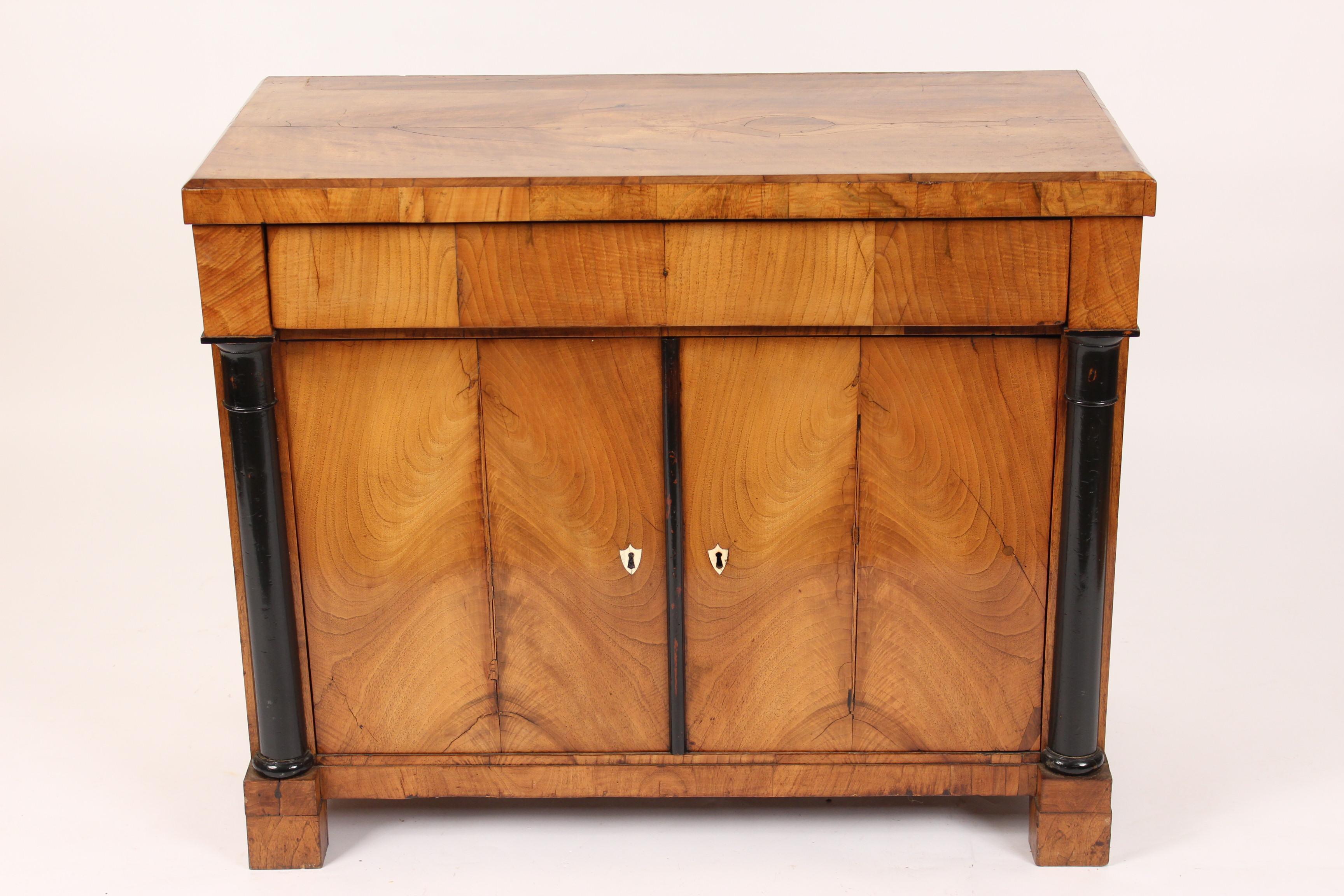 Biedermeier ash and walnut buffet with ebonized columns and bone shield shaped escutcheons, circa 1840. The front and sides are ash the top is walnut.