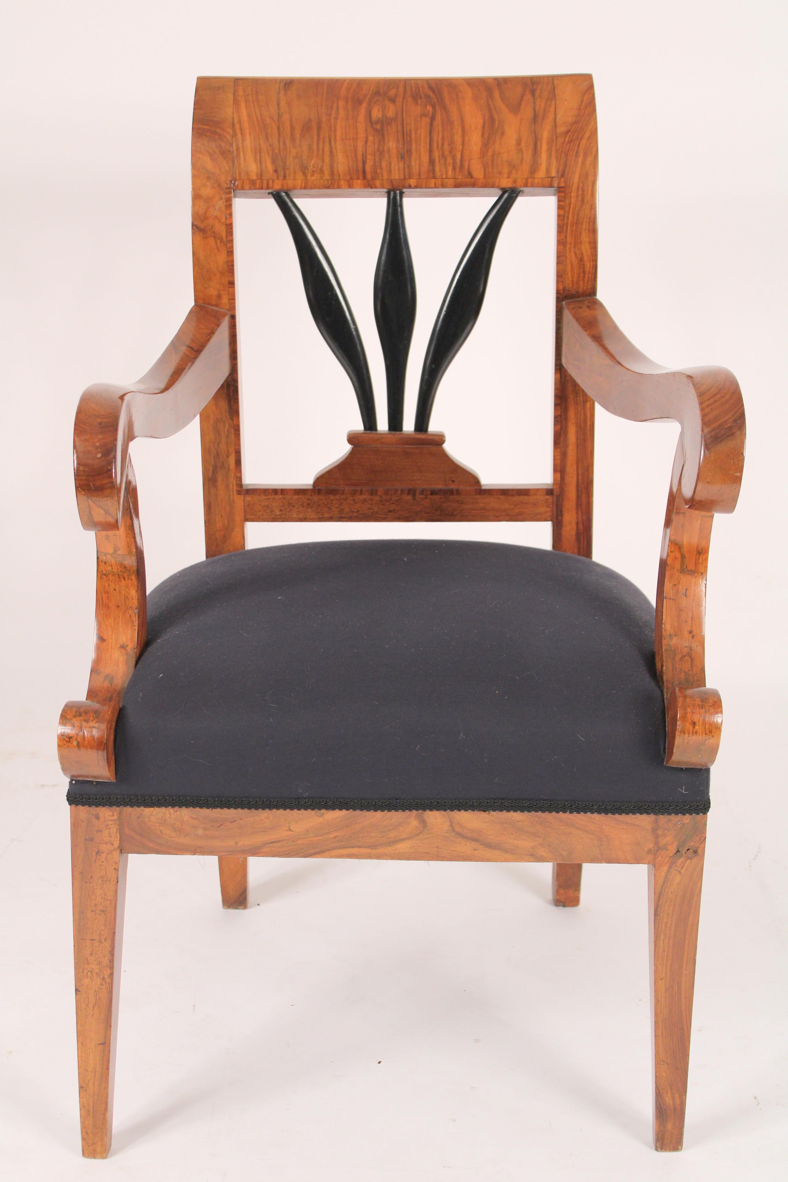 Biedermeier burl walnut armchair, circa 1835. With a nicely figuered burl walnut crest rail, ebonized wheat sheath back splat, s shaped arms resting on c scrolled arm supports on square tapered legs.