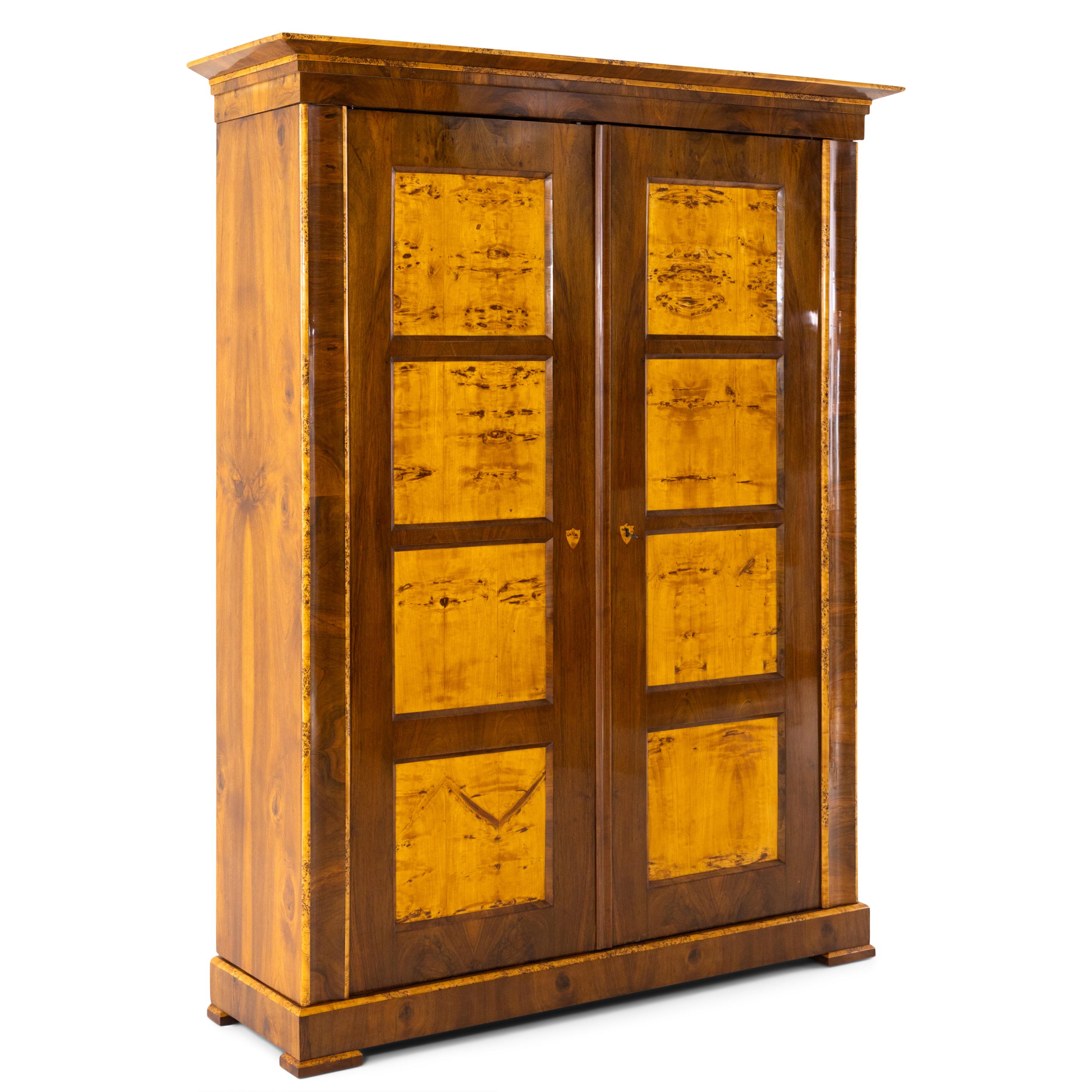 Two-door Biedermeier walnut cabinet with coffered doors and profiled cornice. The edges are set off in poplar.