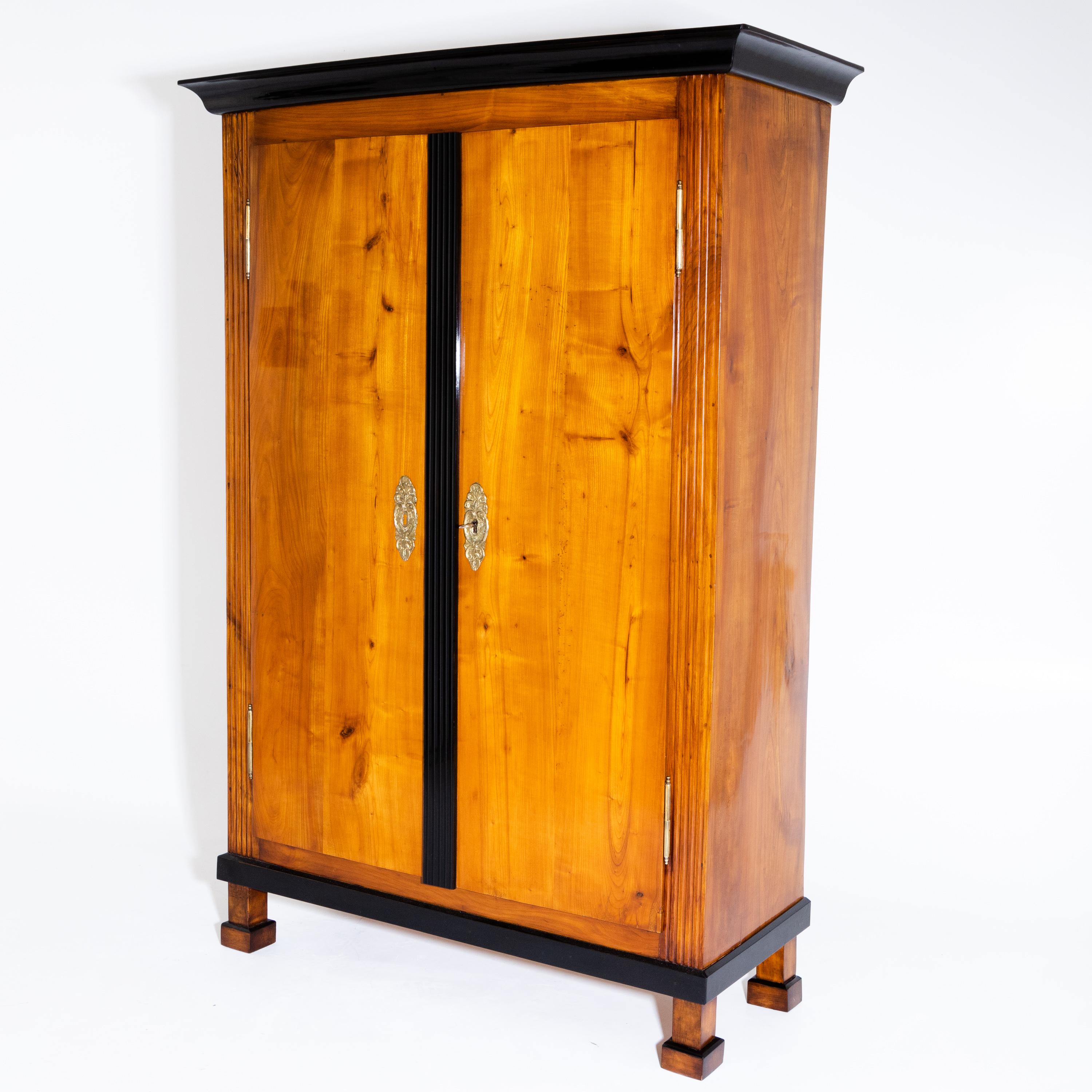 A two-door Biedermeier cabinet with an ebonized, fluted rail and fluted corners. The profiled cornice and the plinth area are also ebonized. The cabinet has been professionally restored and hand polished.