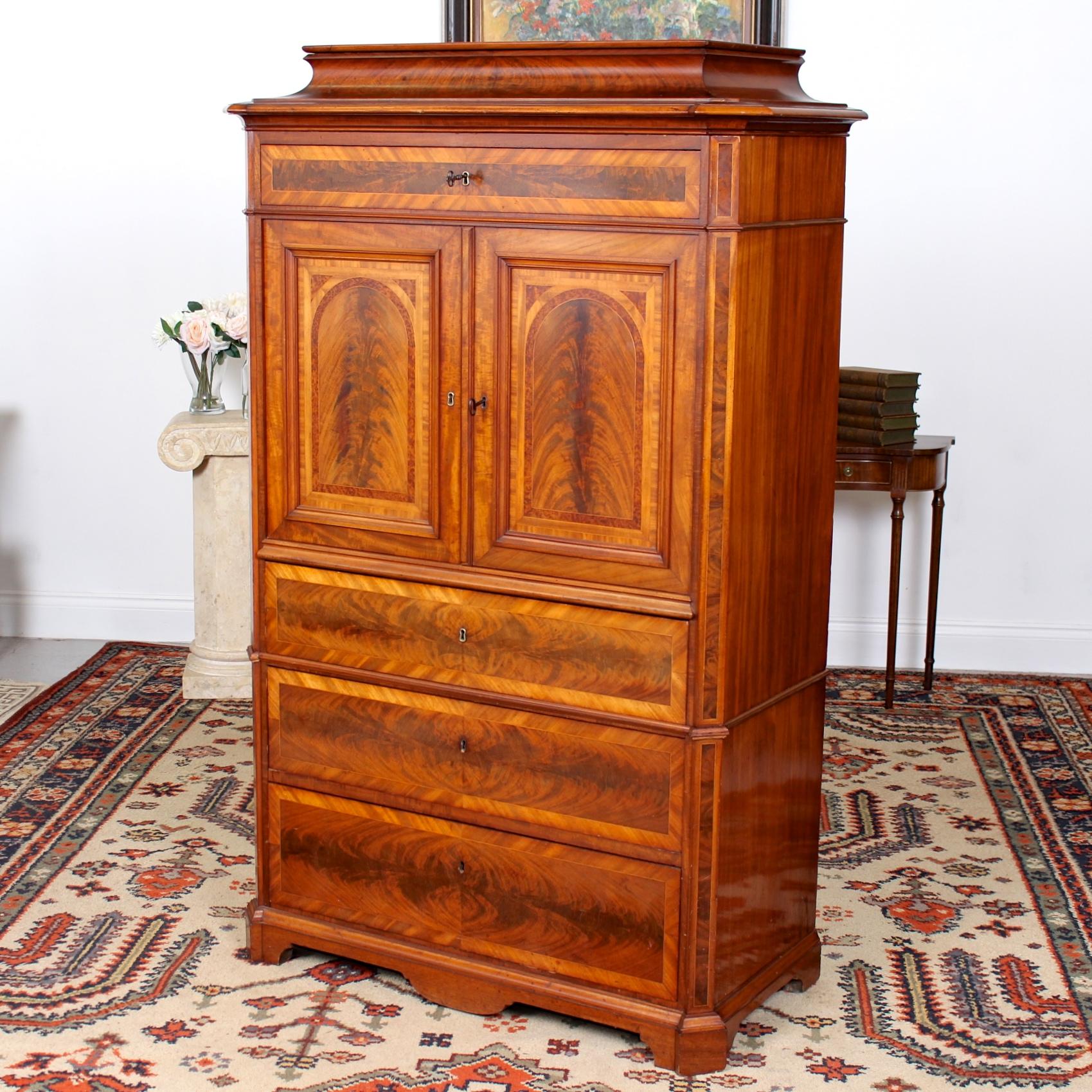 An impressive 19th century Danish Biedermeier secretaire chest.

Boasting fine quality flamed mahogany marquetry work throughout.

The distinctive Biedermeier pagoda top a pair of cupboard doors enclosed a fitted interior briefly comprising
