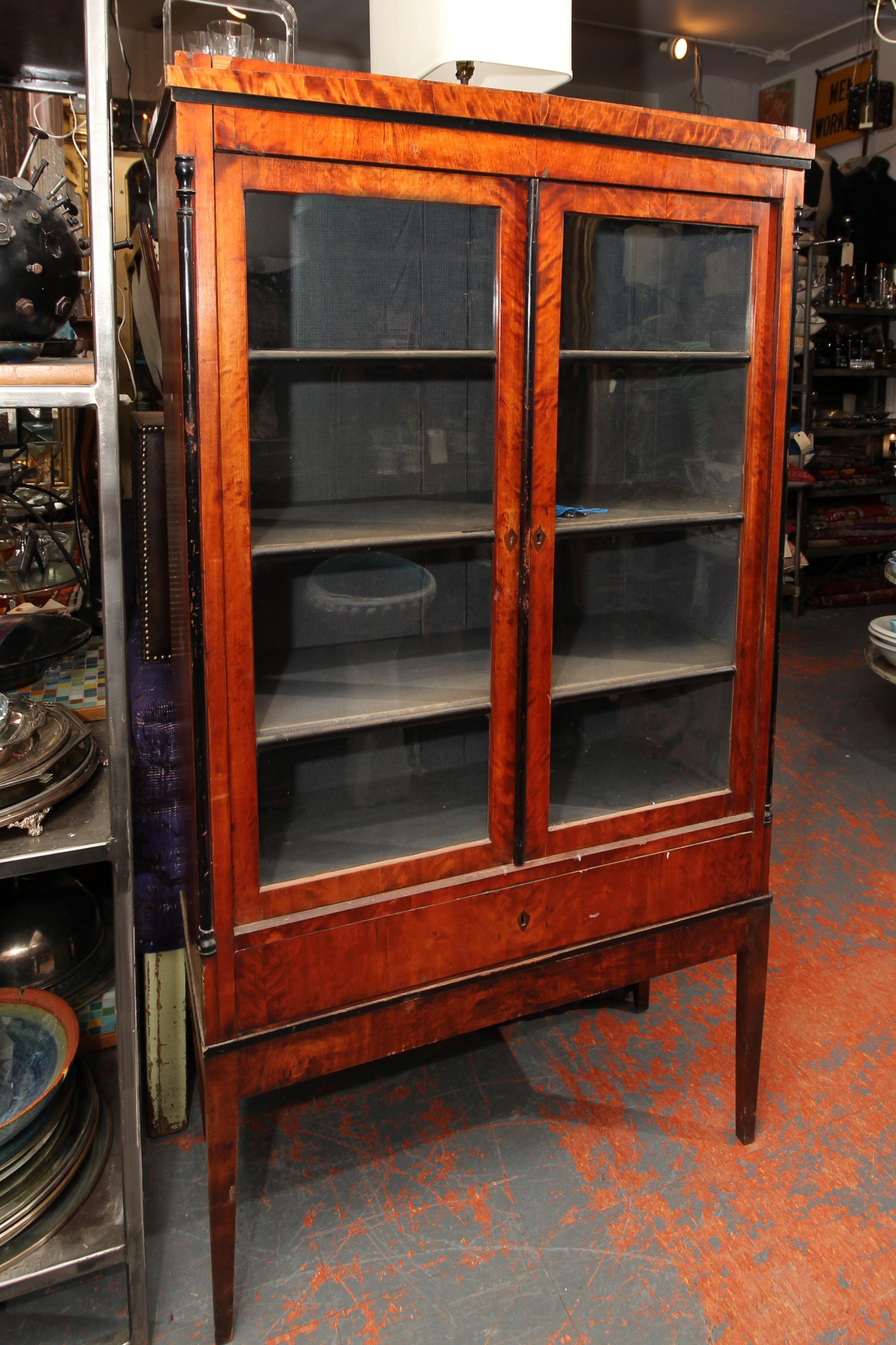 Biedermeier cabinet on lovely tall tapered legs. Old glass in double doors, lock on left side door to keep it from swinging open, and key to lock the cabinet. Interior shelves still lined with blue, as found. Very usable cabinet and a great size.