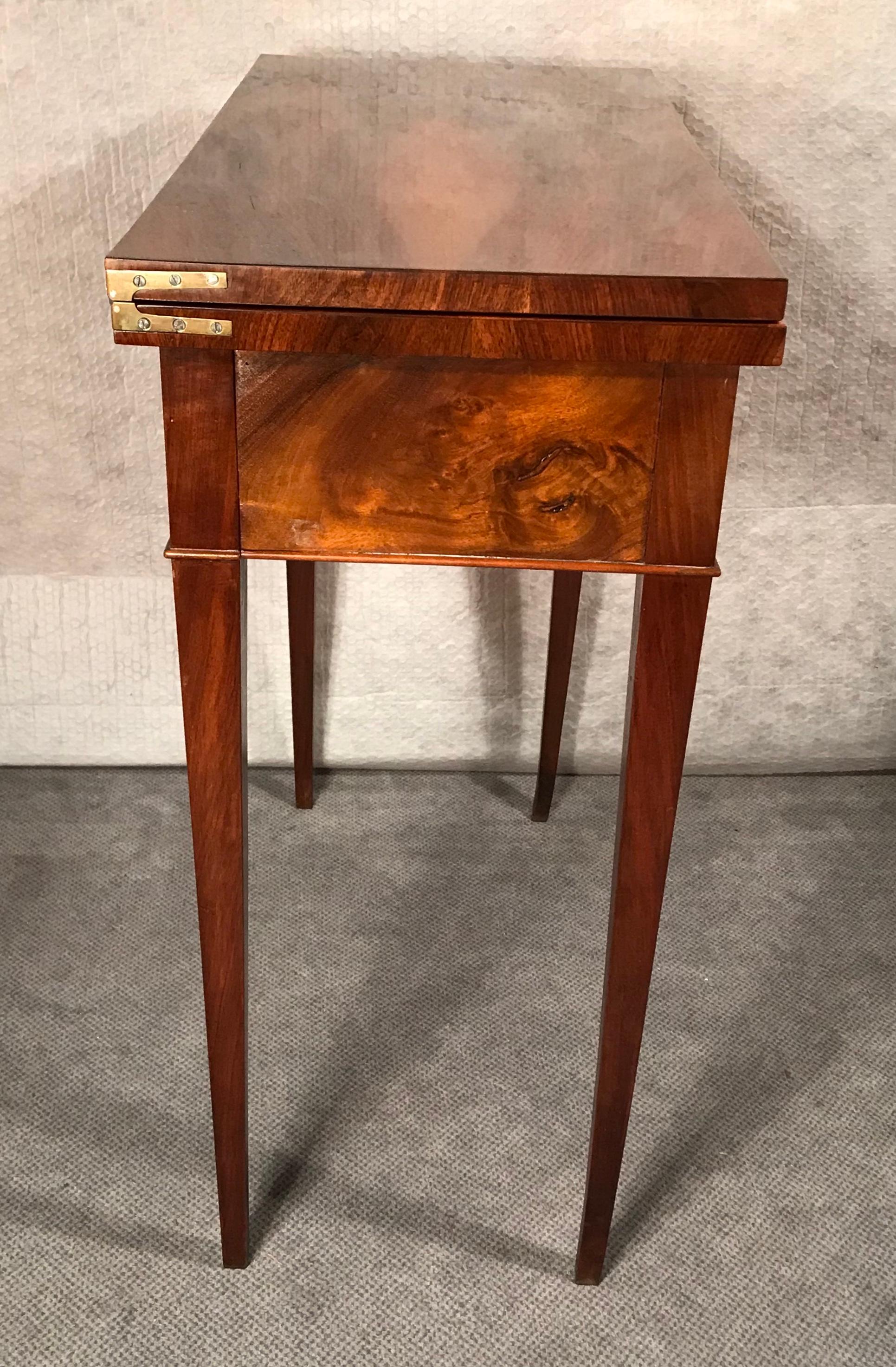 Biedermeier card or console table, South German 1820.
The table has beautiful walnut veneer on top, sides and legs.
The top can be folded out and rests on the pulled out apron and rear legs of the table. The folded out top is covered with green