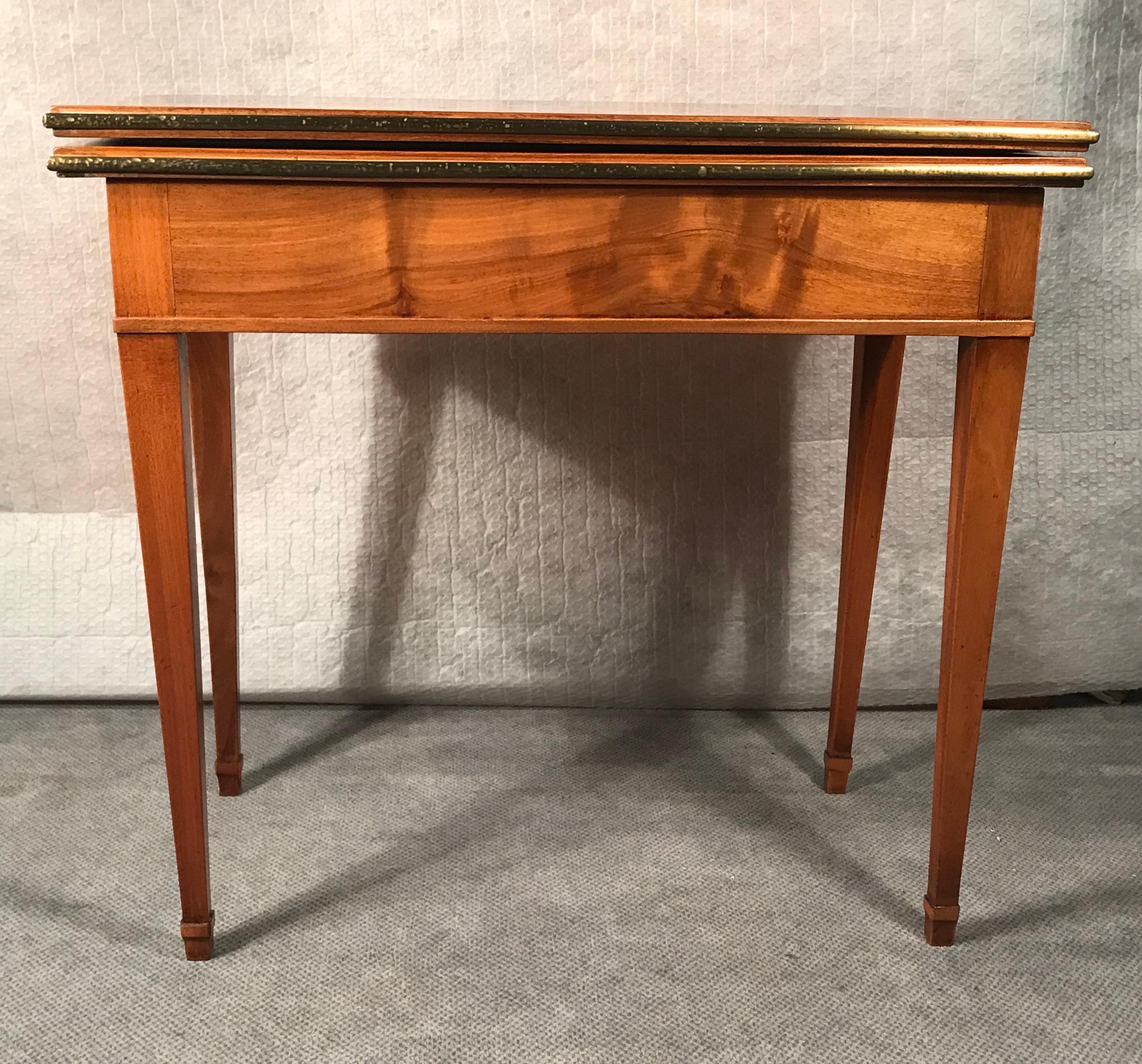 Biedermeier card or console table, South German 1820. The table has beautiful walnut veneer on top, sides and legs. The top can be folded out and turned and then rests on the base of the table. The folded out top is covered with yellow velvet. 
The
