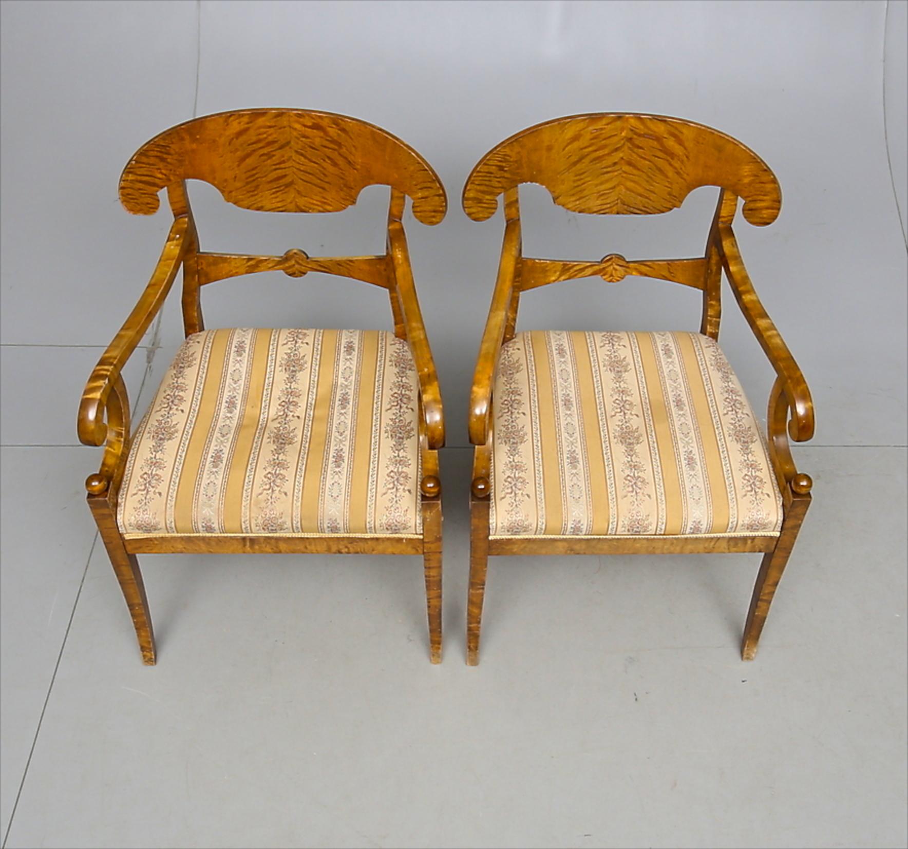 Swedish Biedermeier Empire pair of carver chairs in highly quilted golden birch veneers finished in the Classic honey color French polish finish with ormolu roundel on the arms.

They have fully webbed seats for maximum comfort and the gently