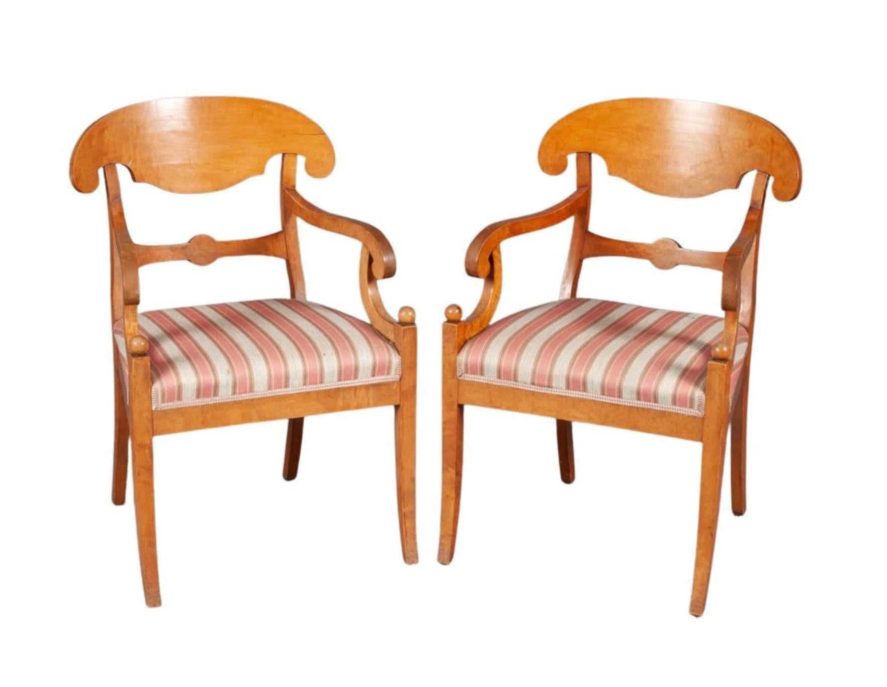 Swedish Biedermeier Empire pair of carver chairs in highly quilted golden birch veneers finished in the Classic honey color French polish finish with ormolu roundel on the arms and fan motifs in the seat back.

They have fully webbed seats for