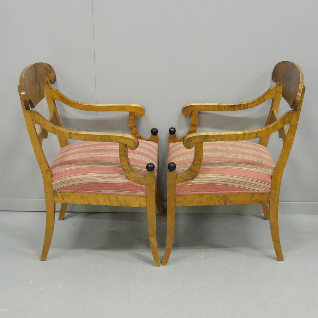 Swedish Biedermeier Empire pair of antique carver chairs in highest grade quilted golden birch veneers finished in the Classic honey oak color French polish finish with rounded arms.

They have fully webbed seats for maximum comfort and the gently