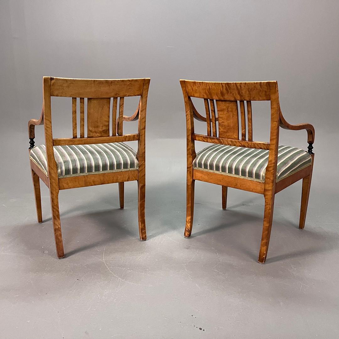 Swedish Biedermeier Empire pair of antique carver chairs in highest grade quilted golden birch veneers finished in the Classic honey oak color French polish finish with rounded arms and the rarer square backs.

They have fully webbed seats for