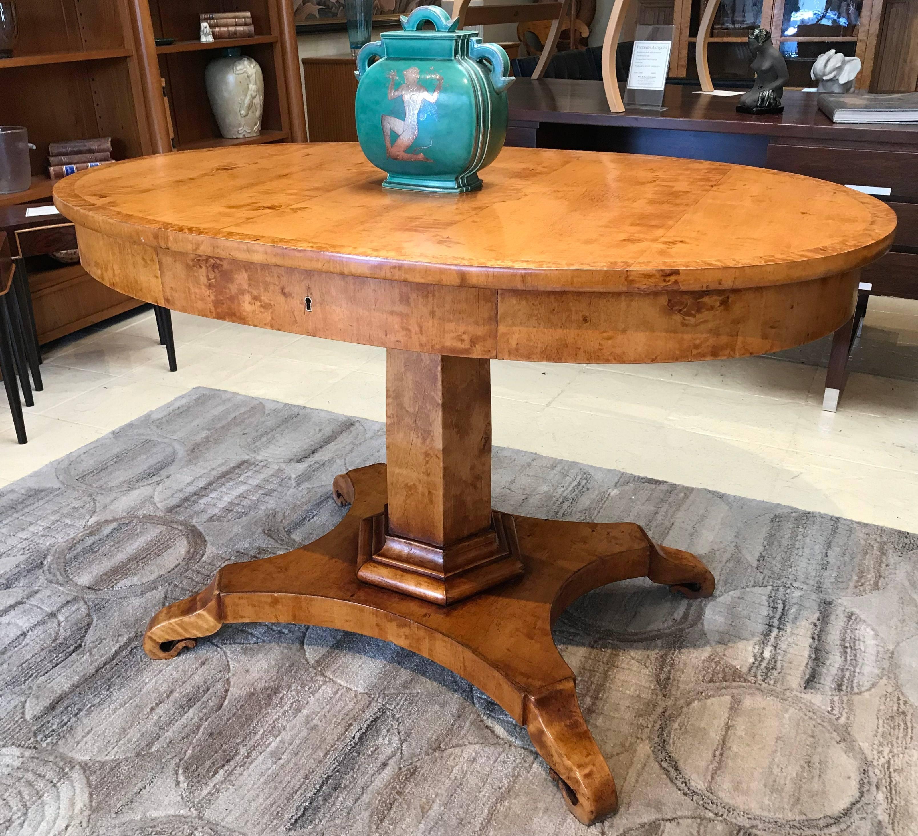 Swedish Biedermeier flame birch centre table with Karelian birch banding to the top. Central curved drawer. The base rests on shaped hand-carved scrolled feet. The birch has a lovely mellow color. This versatile table could be used as a breakfast
