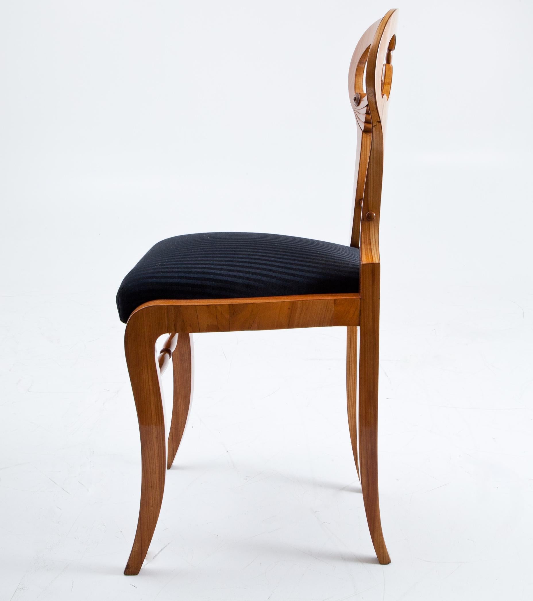Biedermeier cherrywood chair with a turned stretcher between the slightly bent front legs. The shovel-shaped backrests shows turned stretchers as well as fan-carvings in the corners beneath the curved middle slat. The cushioned seat was