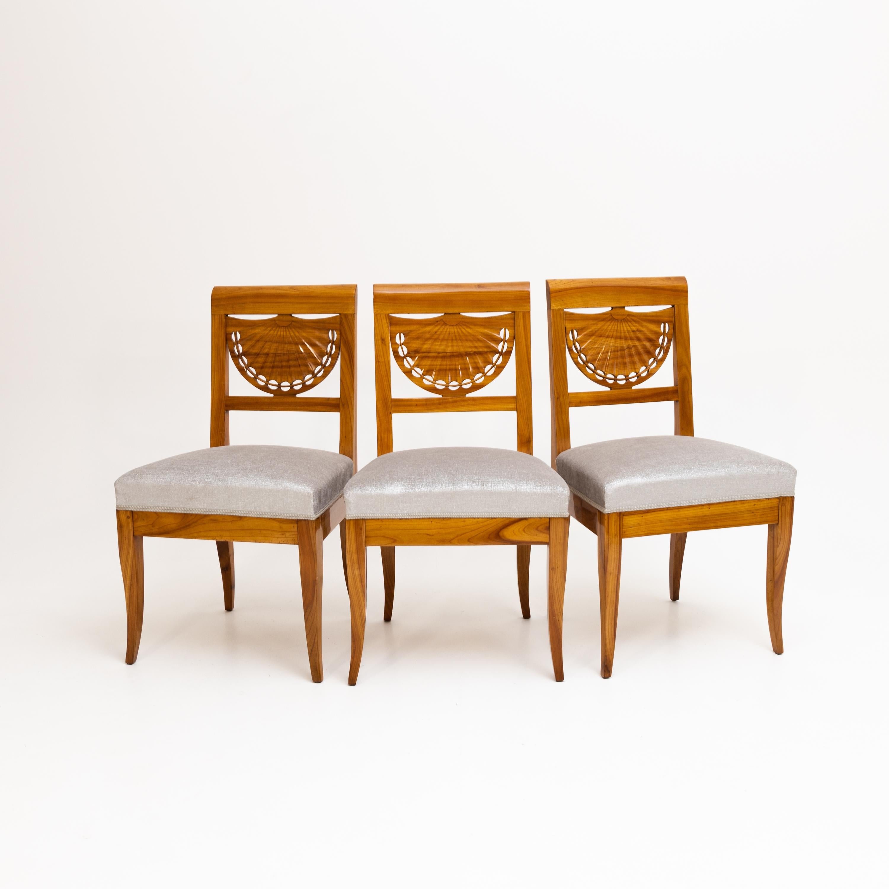 Set of three Biedermeier chairs in cherry wood with fan-shaped backrests and newly upholstered seats.