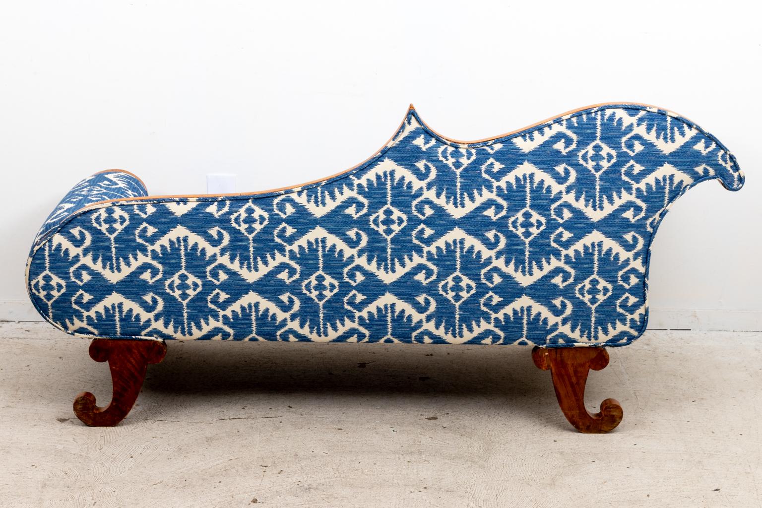 Blue and white upholstered Biedermeier style chaise lounge chair with scrolled arms and an asymmetrical, curved seat back. The legs are carved in the outline of cornucopia baskets. Please note of wear consistent with age including finish loss,
