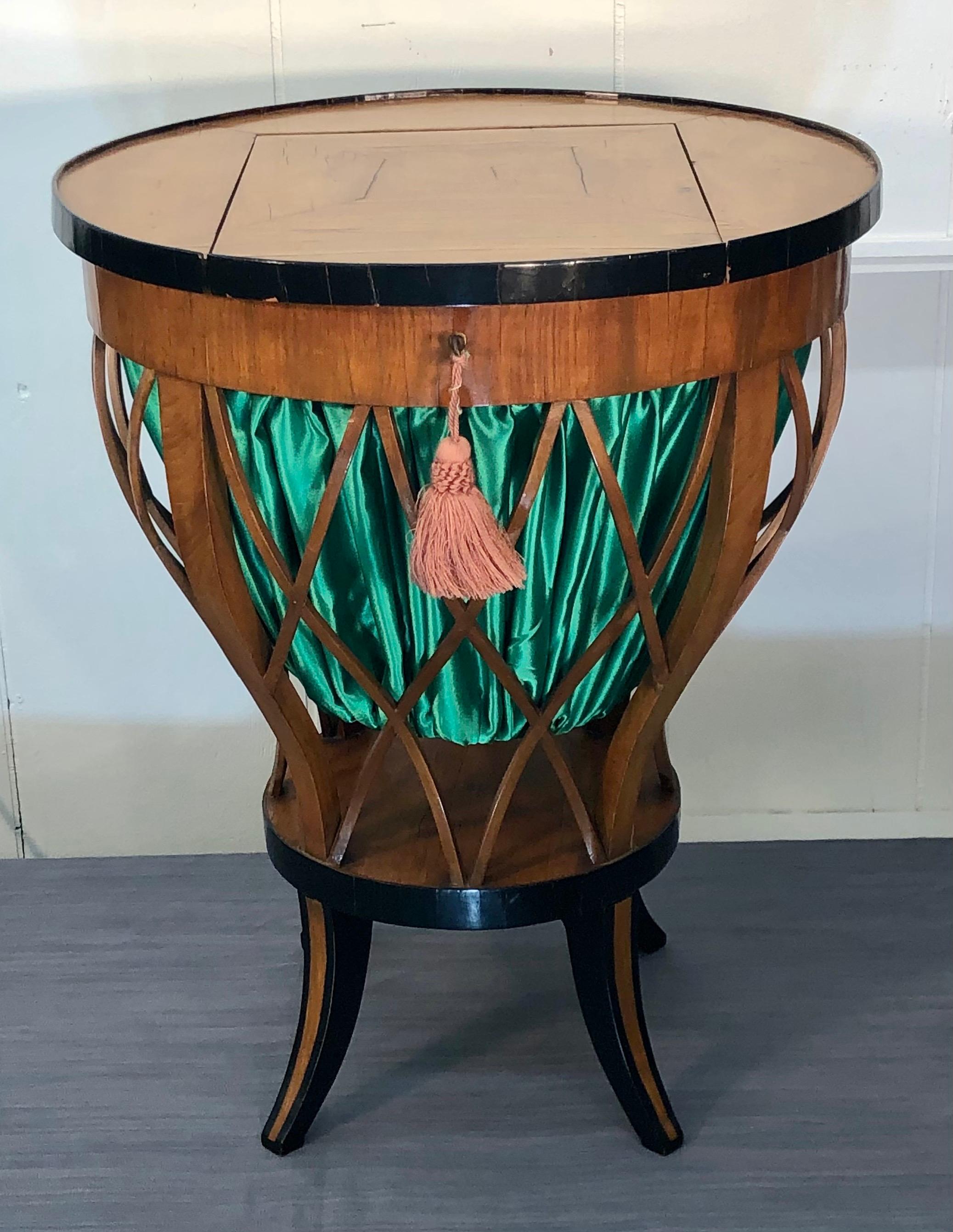 Fashionable South German Biedermeier cherry-veneer and ebonized work table / sewing table. Round cherry-veneered top surrounded by ebonized ring with a hinged door to access the green silk basket enclosed with in solid cherry lattice work. The legs