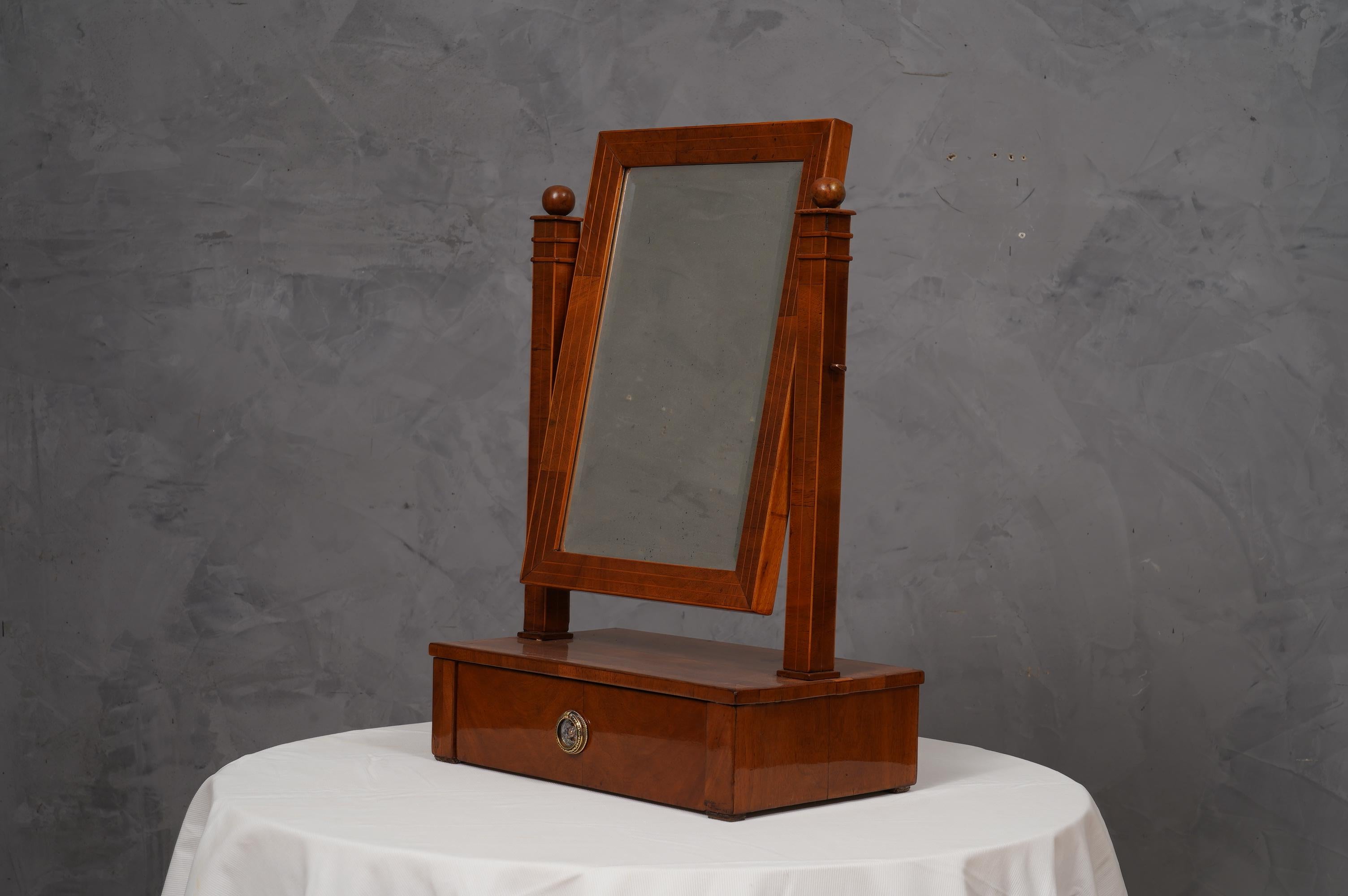 Beautiful and very special Biedermeier vanity mirror, refined and classy with a very simple design.

The mirror is formed by a structure in soft wood, which has been veneered in cherry wood. Its structure is very simple, under a base with a small