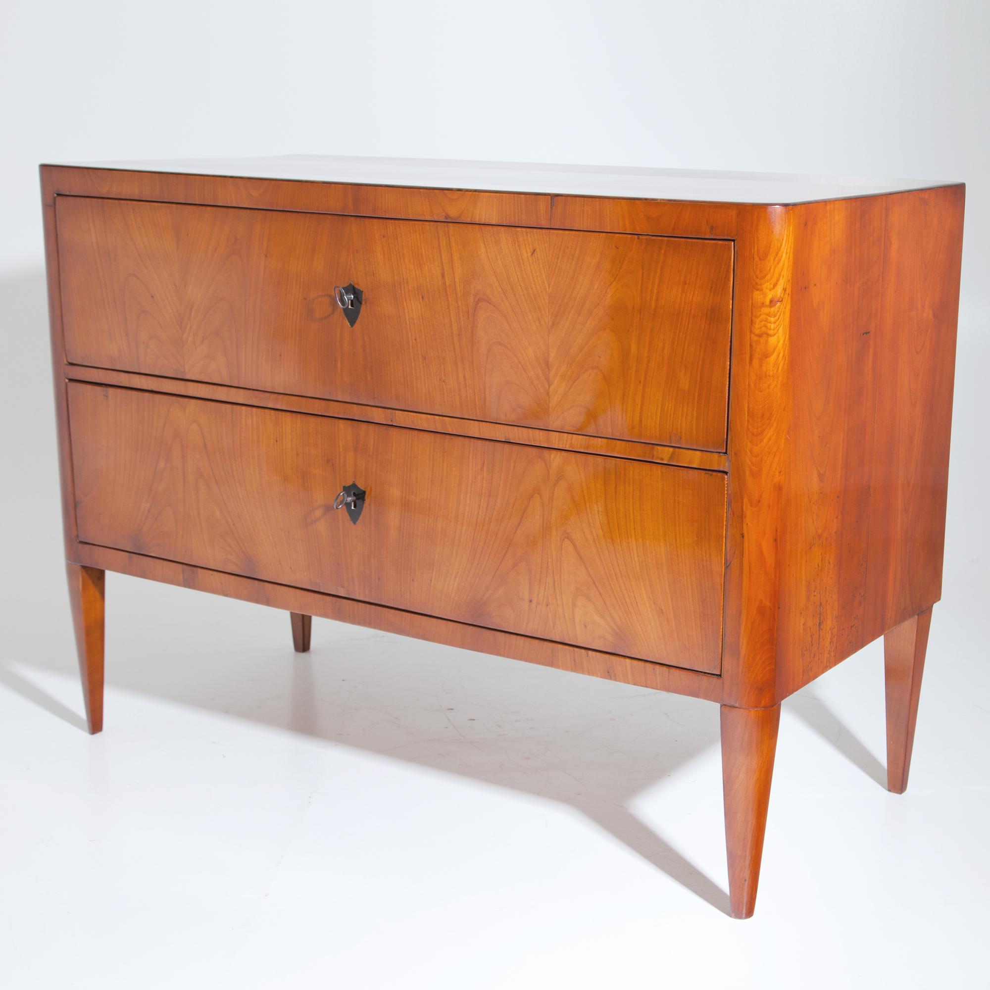 Biedermeier cherrywood chest of drawers with two drawers, standing on rounded pointed feet, the escutcheons are ebonized. Expertly restored condition.